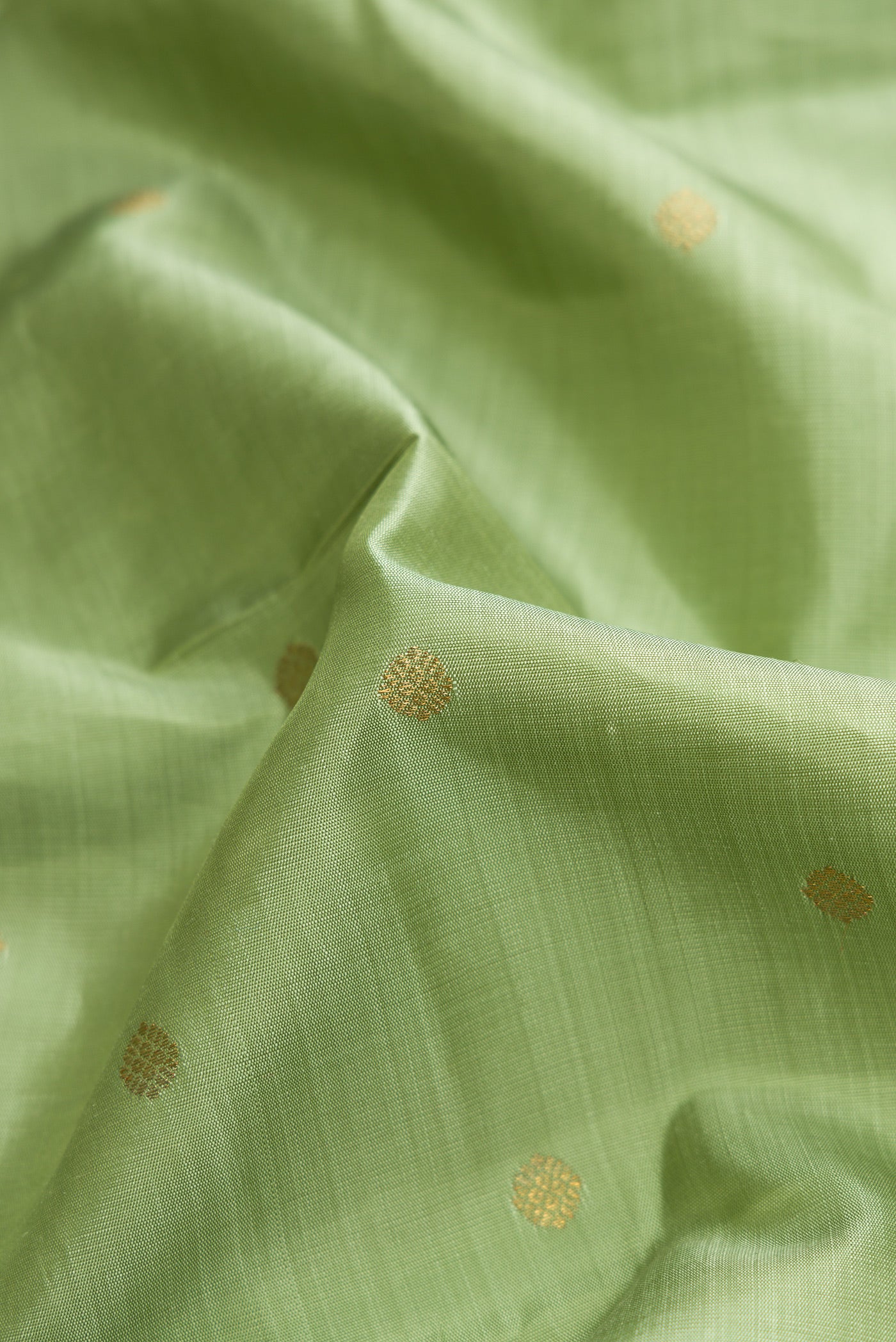 Close up of Pure Silk Pure Zari Pista Green Dual Tone Kanjivaram Saree with Zari Butta on the body and Zari Border.  displaying folds