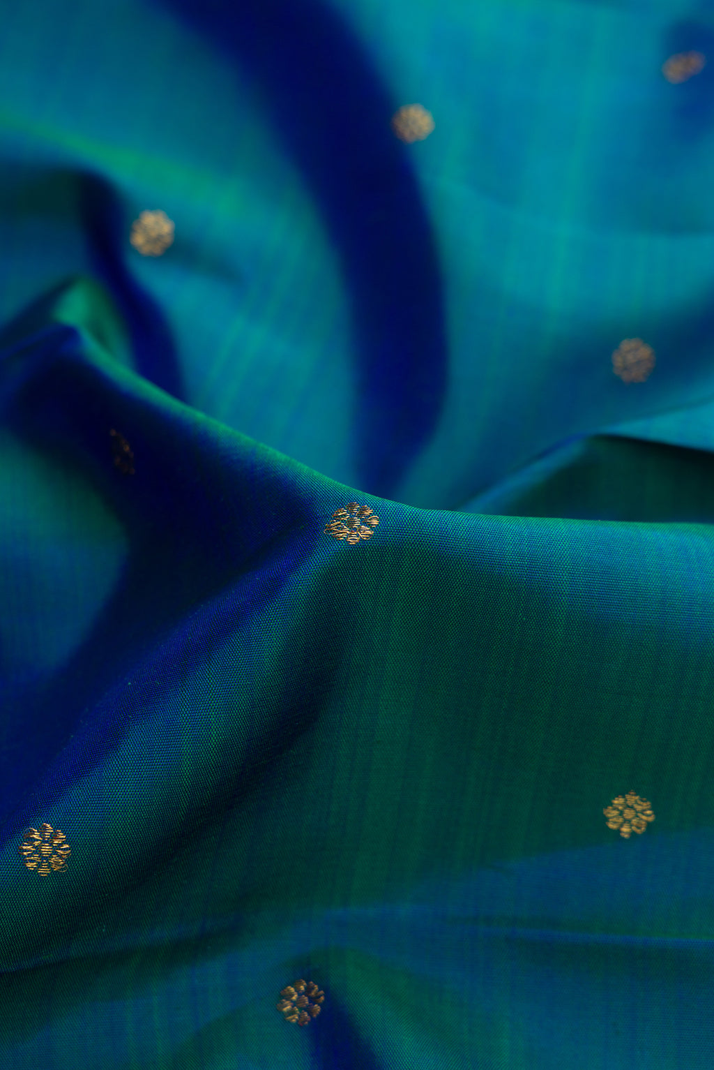 Close up of Pure Silk Pure Zari Peacock Blue Dual Tone Kanjivaram Saree with Zari Butta on the body and Zari Border.  displaying folds