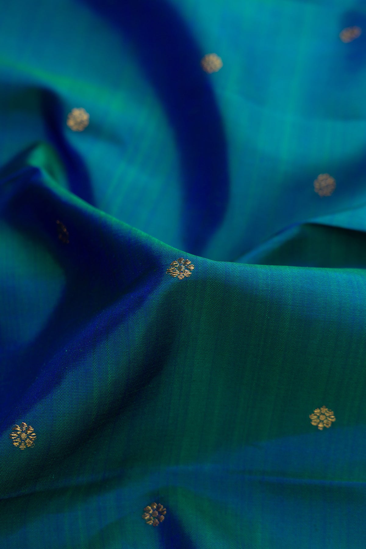 Close up of Pure Silk Pure Zari Peacock Blue Dual Tone Kanjivaram Saree with Zari Butta on the body and Zari Border.  displaying folds