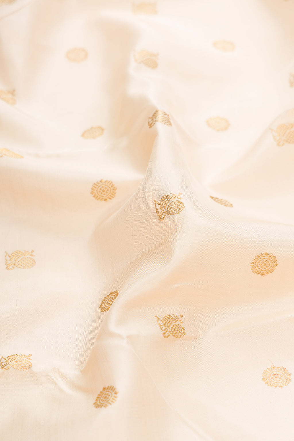 Close up of Pure Silk Pure Zari Off White Dual Tone Kanjivaram Saree with Zari Butta on the body and Zari Border.  displaying folds