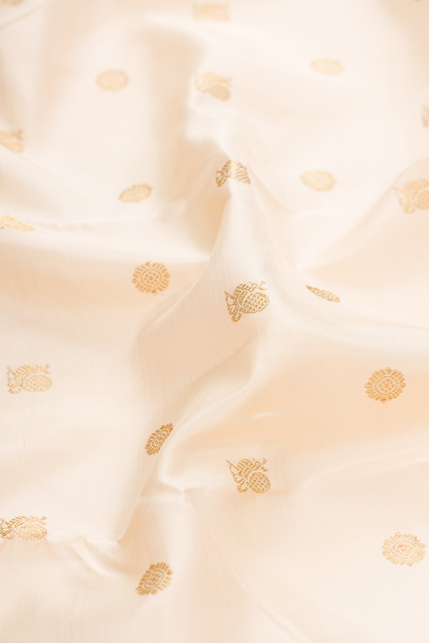 Close up of Pure Silk Pure Zari Off White Dual Tone Kanjivaram Saree with Zari Butta on the body and Zari Border.  displaying folds