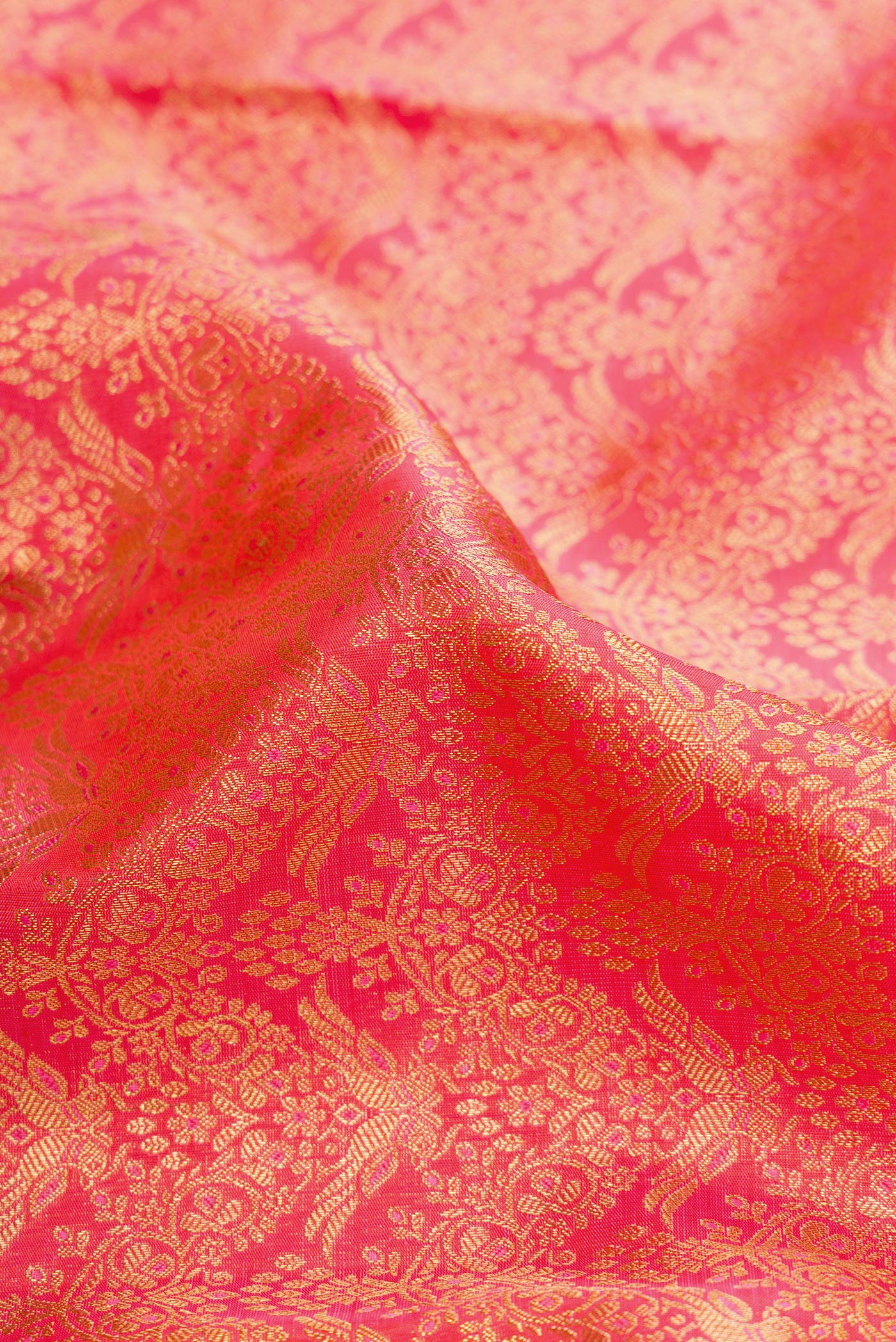 Close up of Pure Silk Pure Zari Coral Dual Tone Kanjivaram Saree with Zari Brocade on the body and Zari Border.  displaying folds