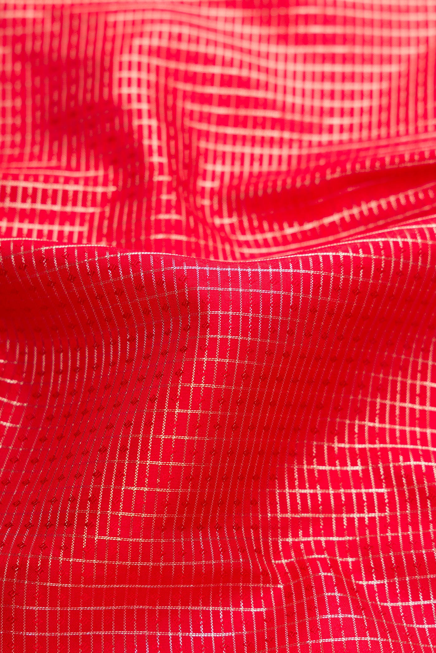 Close up of Red Dual Tone Kanchipuram Silk Saree with Checked design on the body and Zari Border.  displaying folds