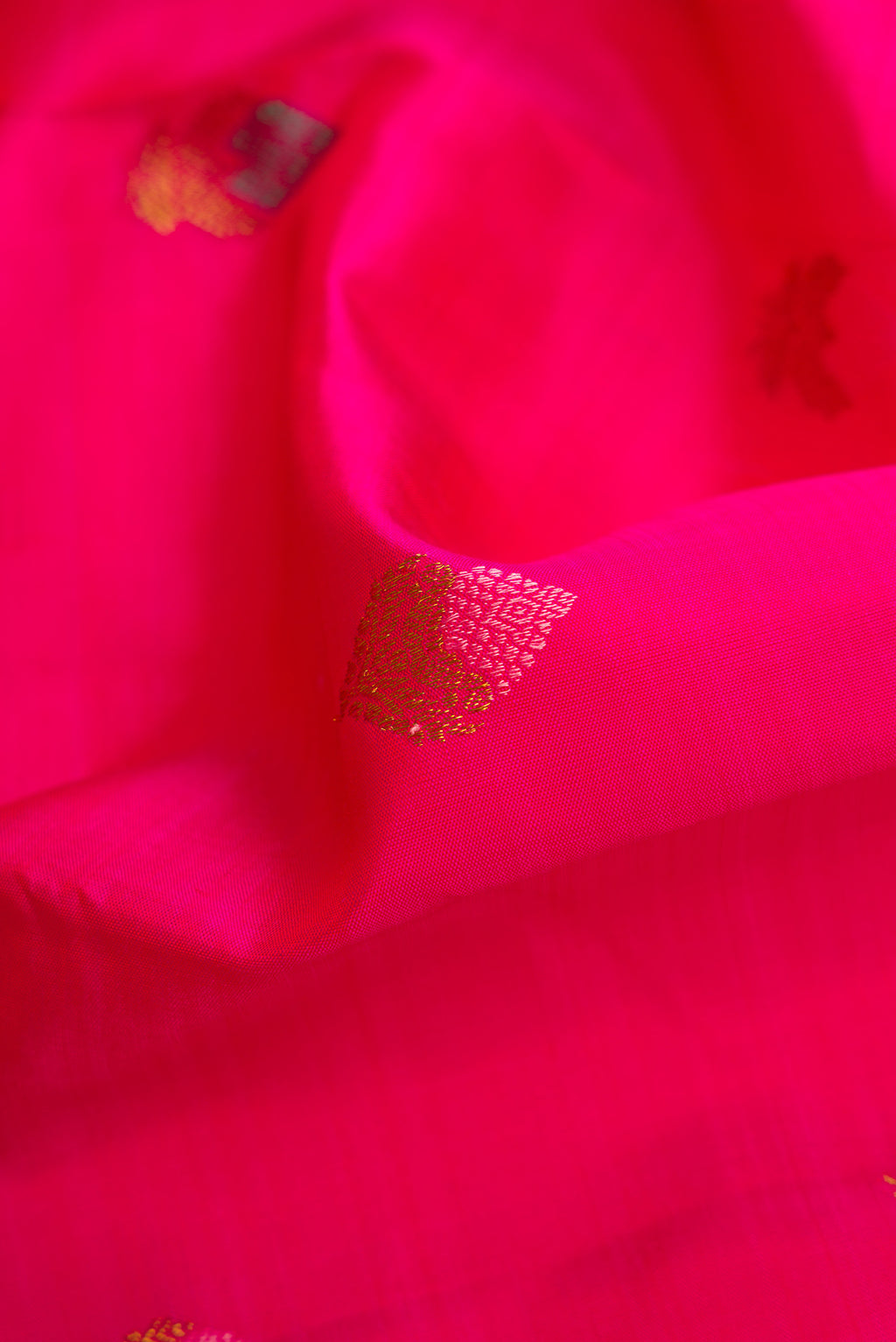 Close up of Pure Silk Pure Zari Pink Dual Tone Kanjivaram Saree with Zari And Thread Butta on the body and Zari Border.  displaying folds