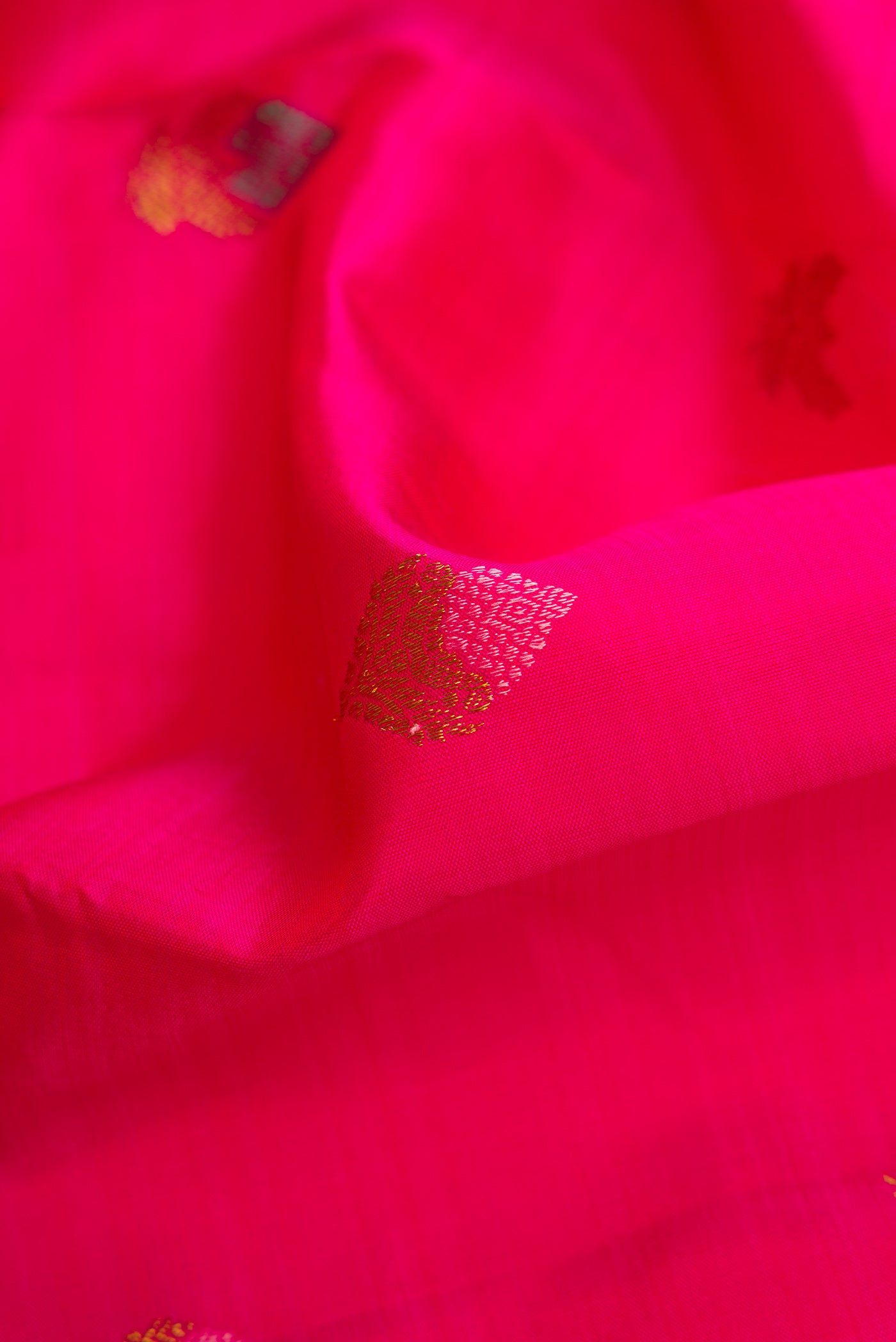 Close up of Pure Silk Pure Zari Pink Dual Tone Kanjivaram Saree with Zari And Thread Butta on the body and Zari Border.  displaying folds