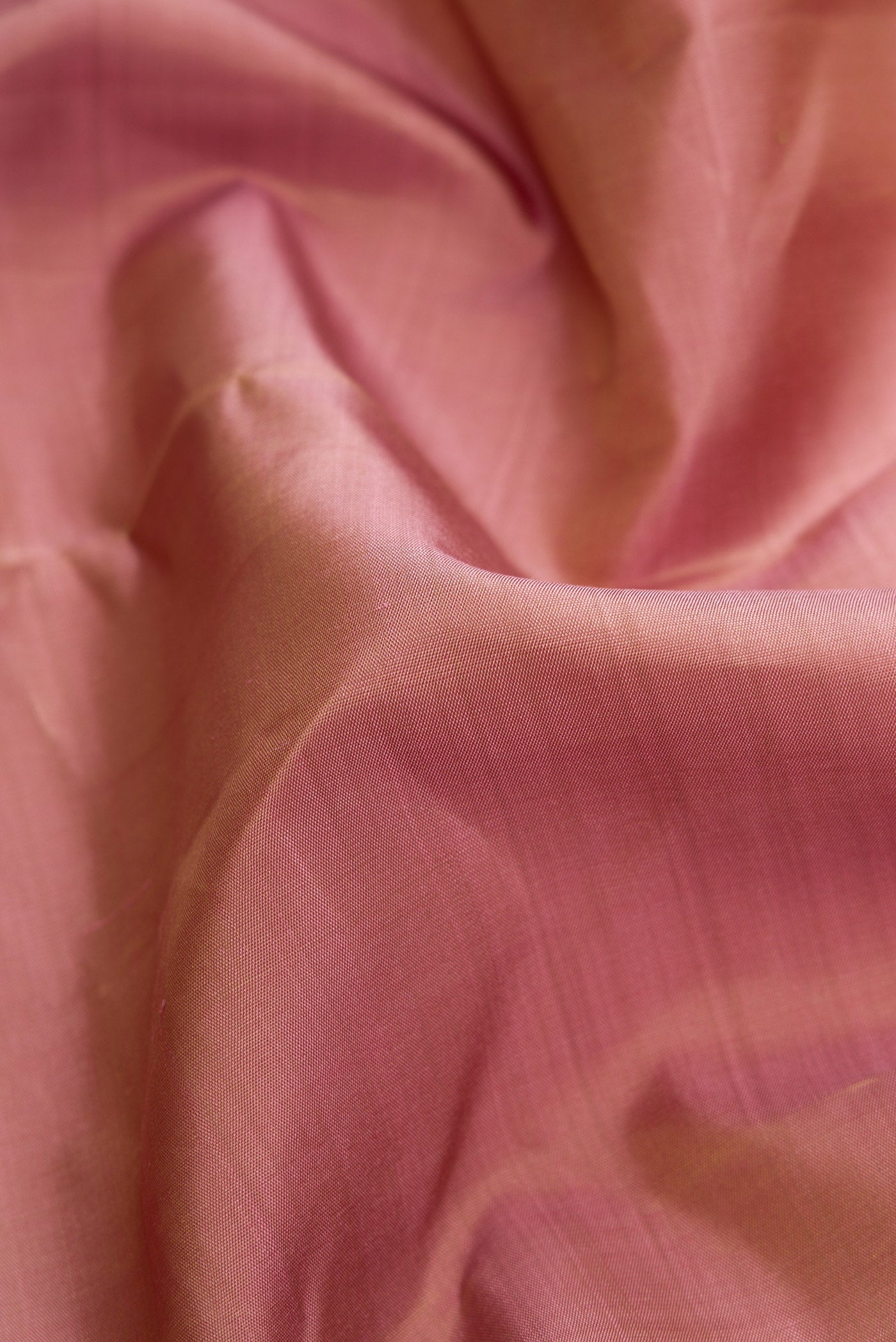 Close up of Pure Silk Pure Zari Rose Gold Dual Tone Kanchipuram Saree with Zari Butta on the body and Zari Border.  displaying folds