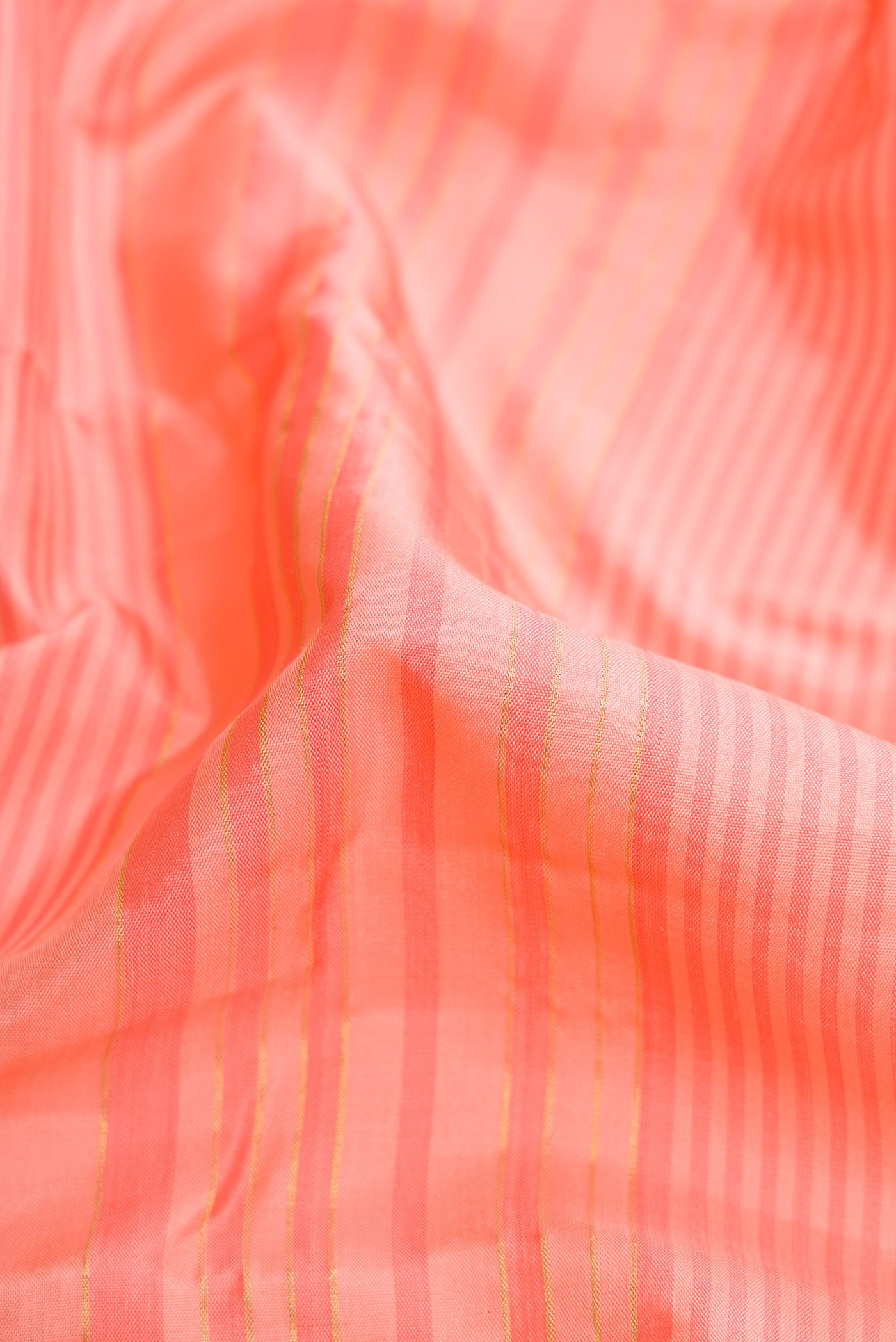 Close up of Peach Dual Tone Kanjivaram Silk Saree with Stripes on the body and Zari Border.  displaying folds