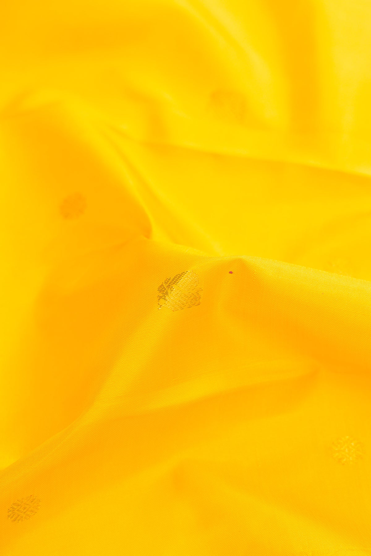 Close up of Pure Silk Pure Zari Yellow Dual Tone Kanjivaram Saree with Zari Butta on the body and Zari Border.  displaying folds