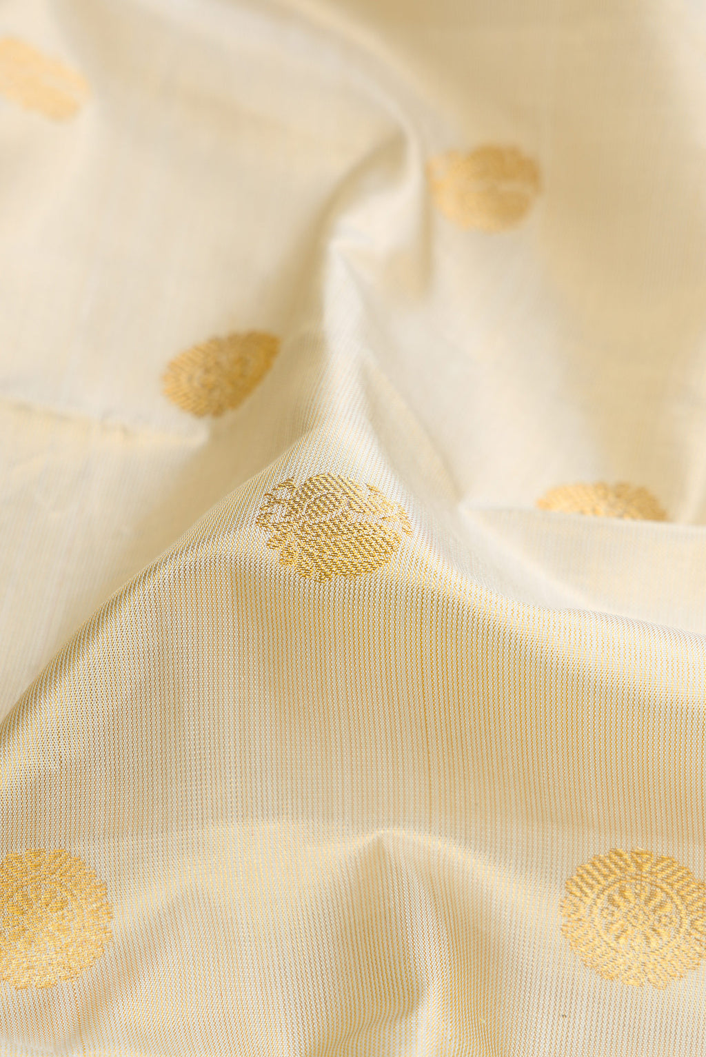 Close up of Beige Dual Tone Kanjivaram Silk Saree with Zari Butta on the body and Zari And Thread Border.  displaying folds