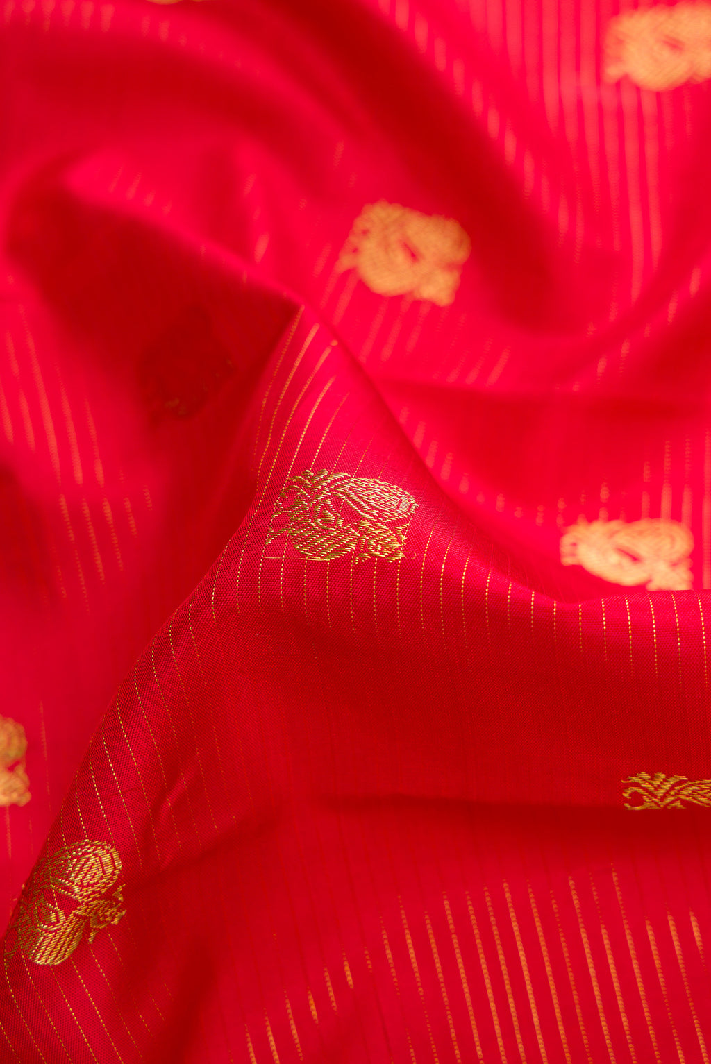 Close up of Red Dual Tone Kanchipuram Silk Saree with Zari Butta on the body and Zari Border.  displaying folds