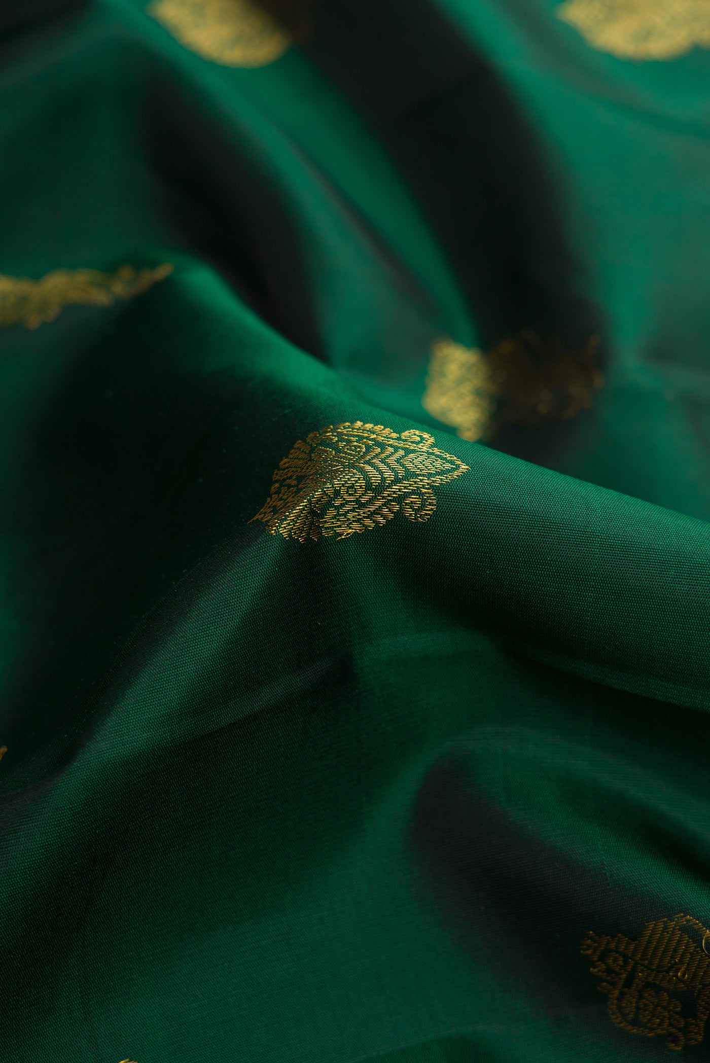 Close up of Pure Silk Pure Zari Green Dual Tone Kanjivaram Saree with Zari Butta on the body and Zari Border.  displaying folds