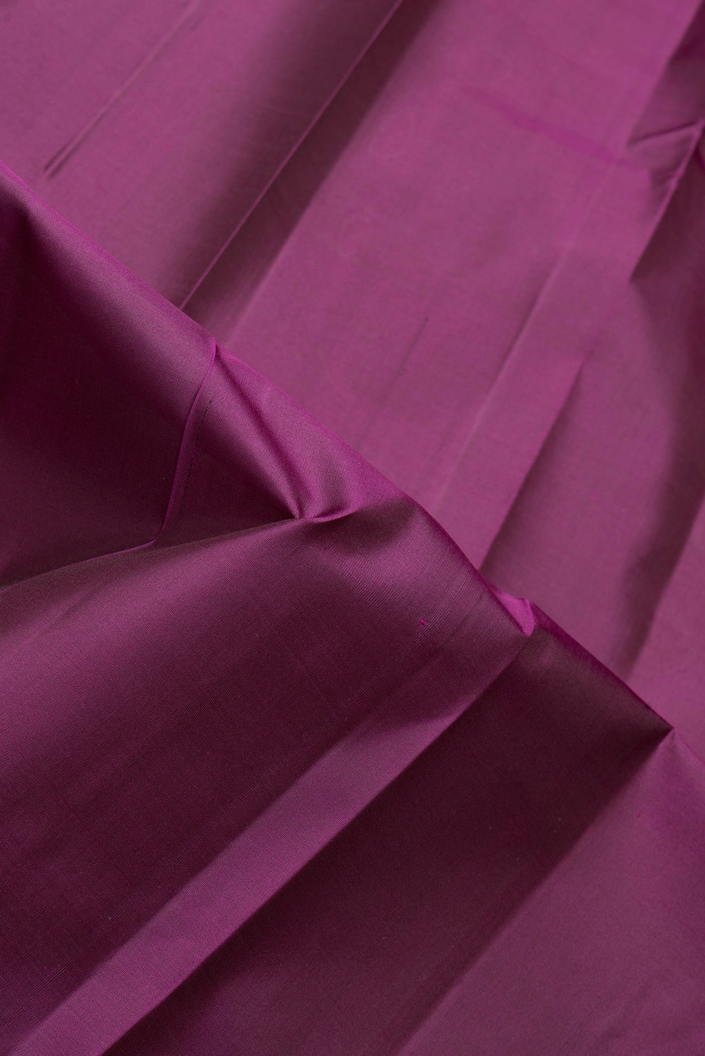 Close up of Magenta Dual Tone Kanjivaram Silk Saree with Plain Body and Zari Border.  displaying folds