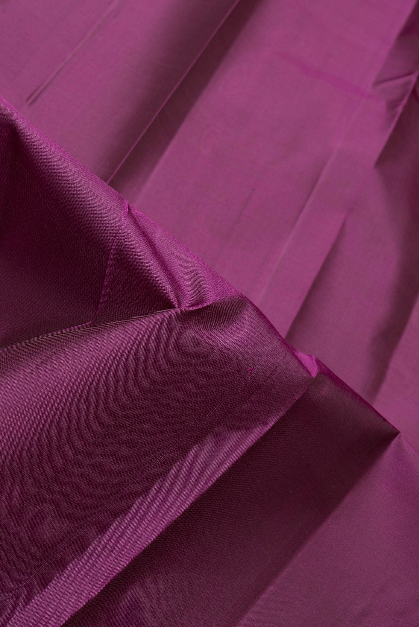 Close up of Magenta Dual Tone Kanjivaram Silk Saree with Plain Body and Zari Border.  displaying folds