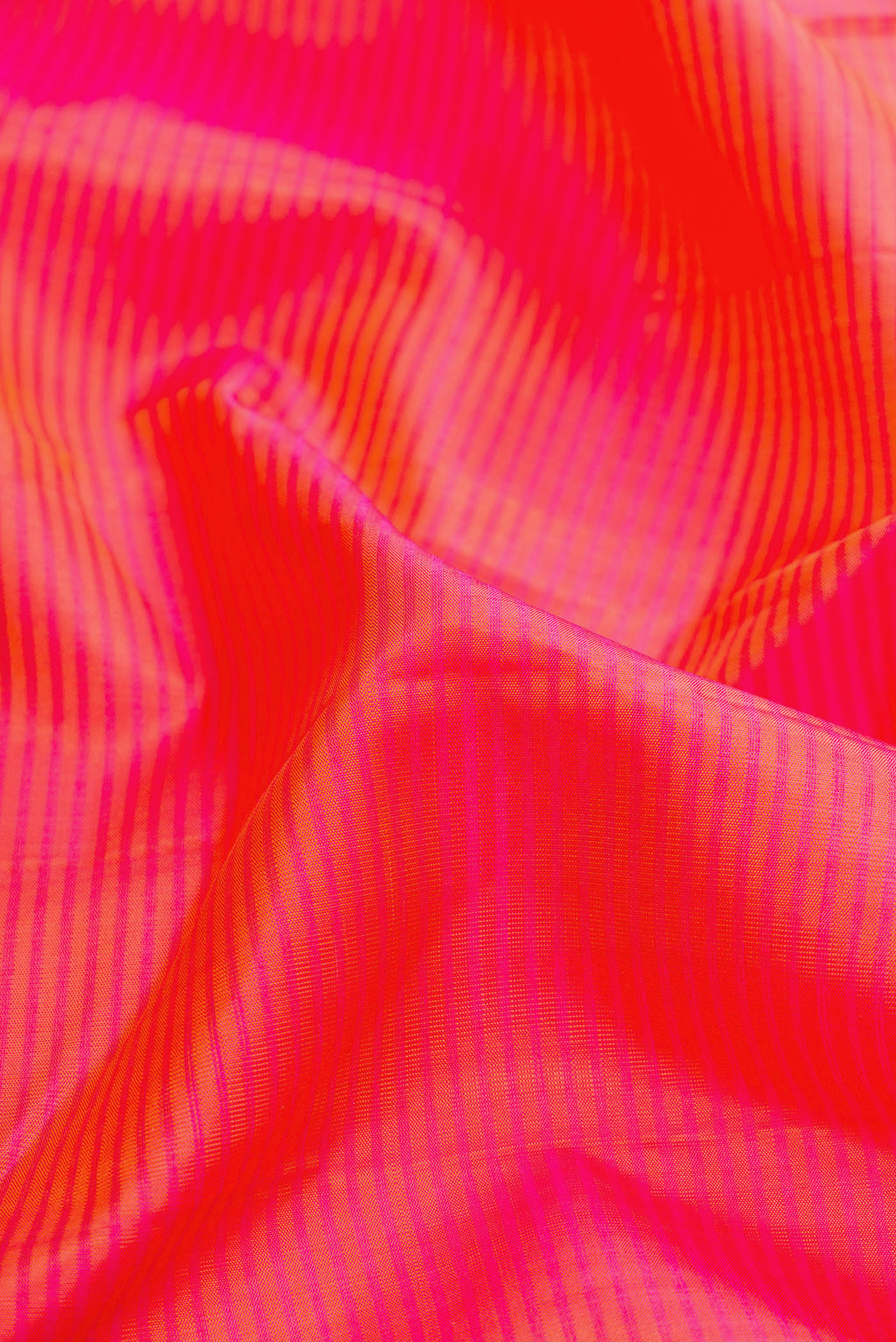 Close up of Coral Dual Tone Kanjivaram Silk Saree with Stripes on the body and Zari Border.  displaying folds