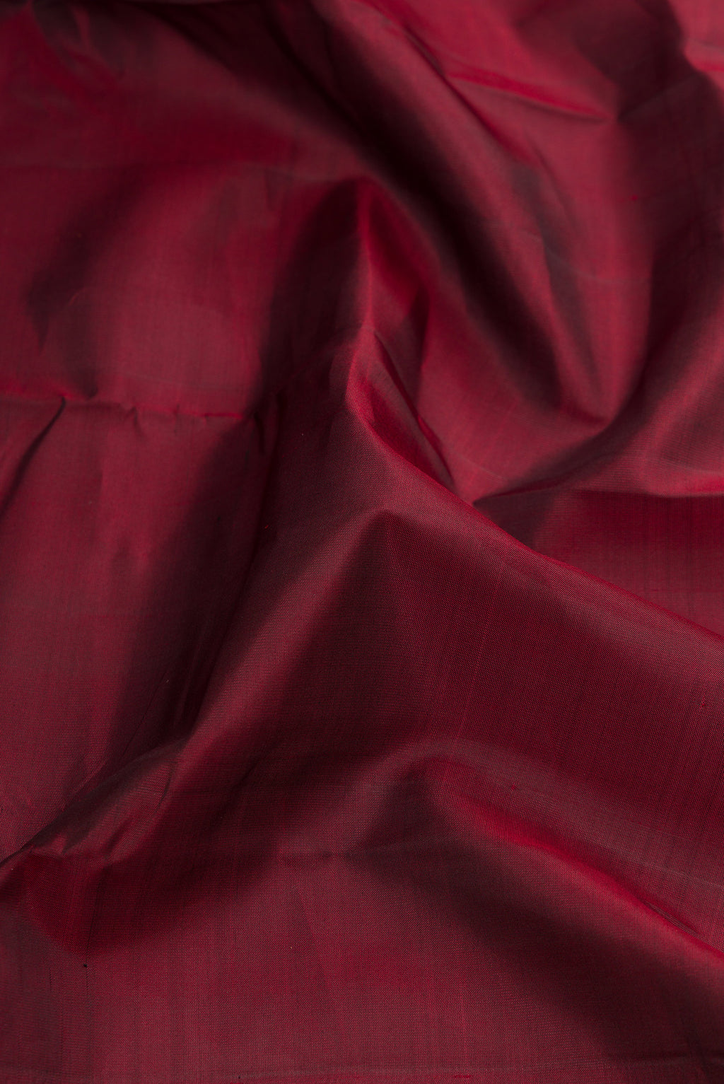 Close up of Maroon Dual Tone Kanchipuram Silk Saree with Plain Body and Zari Border.  displaying folds