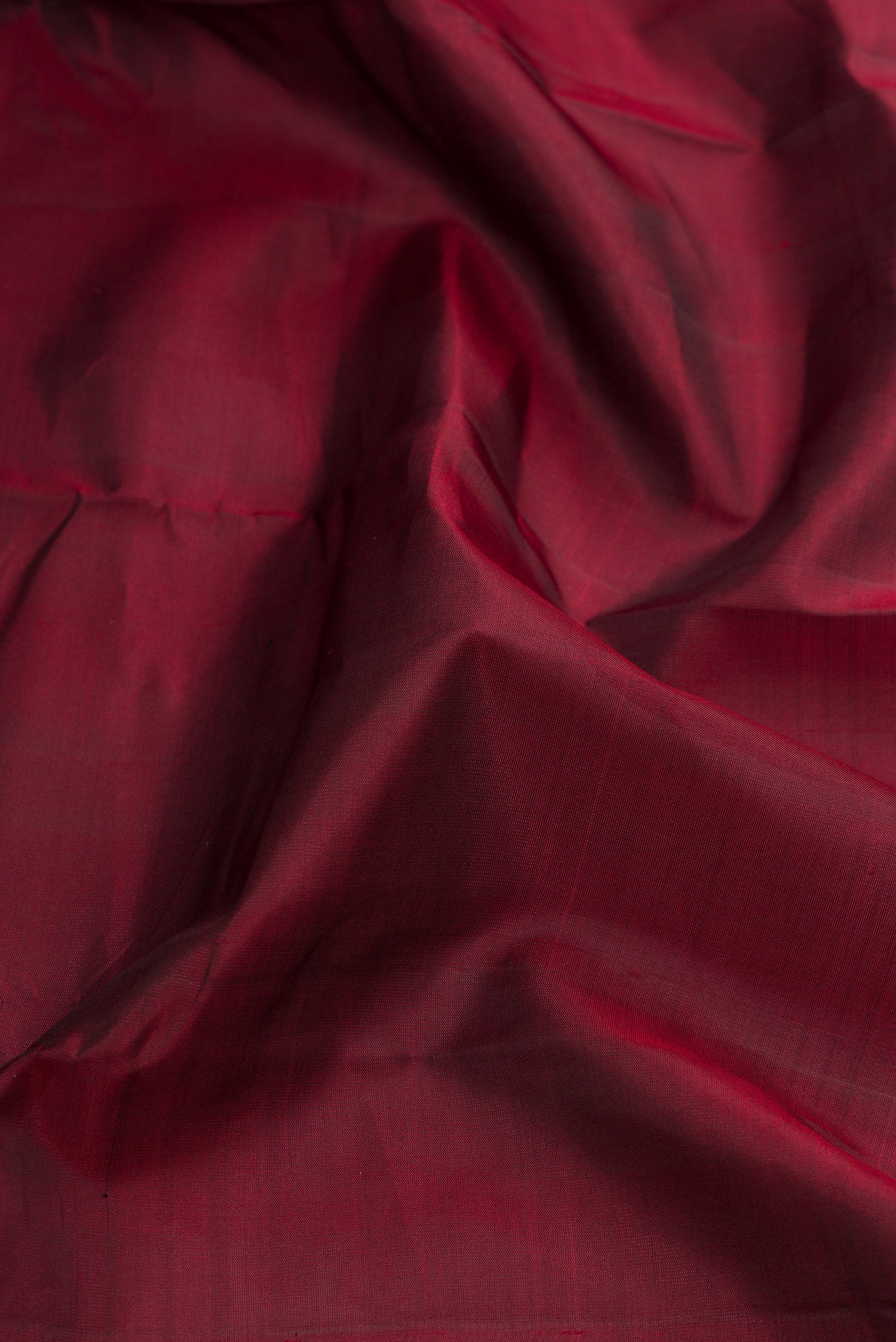 Close up of Maroon Dual Tone Kanchipuram Silk Saree with Plain Body and Zari Border.  displaying folds