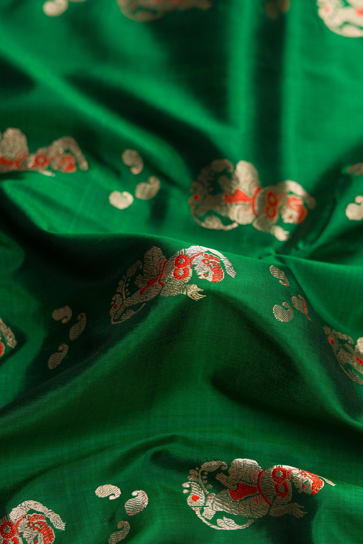 Close up of Green Dual Tone Baluchari Silk Saree with Zari And Thread Butta on the body and Thread Border.  displaying folds