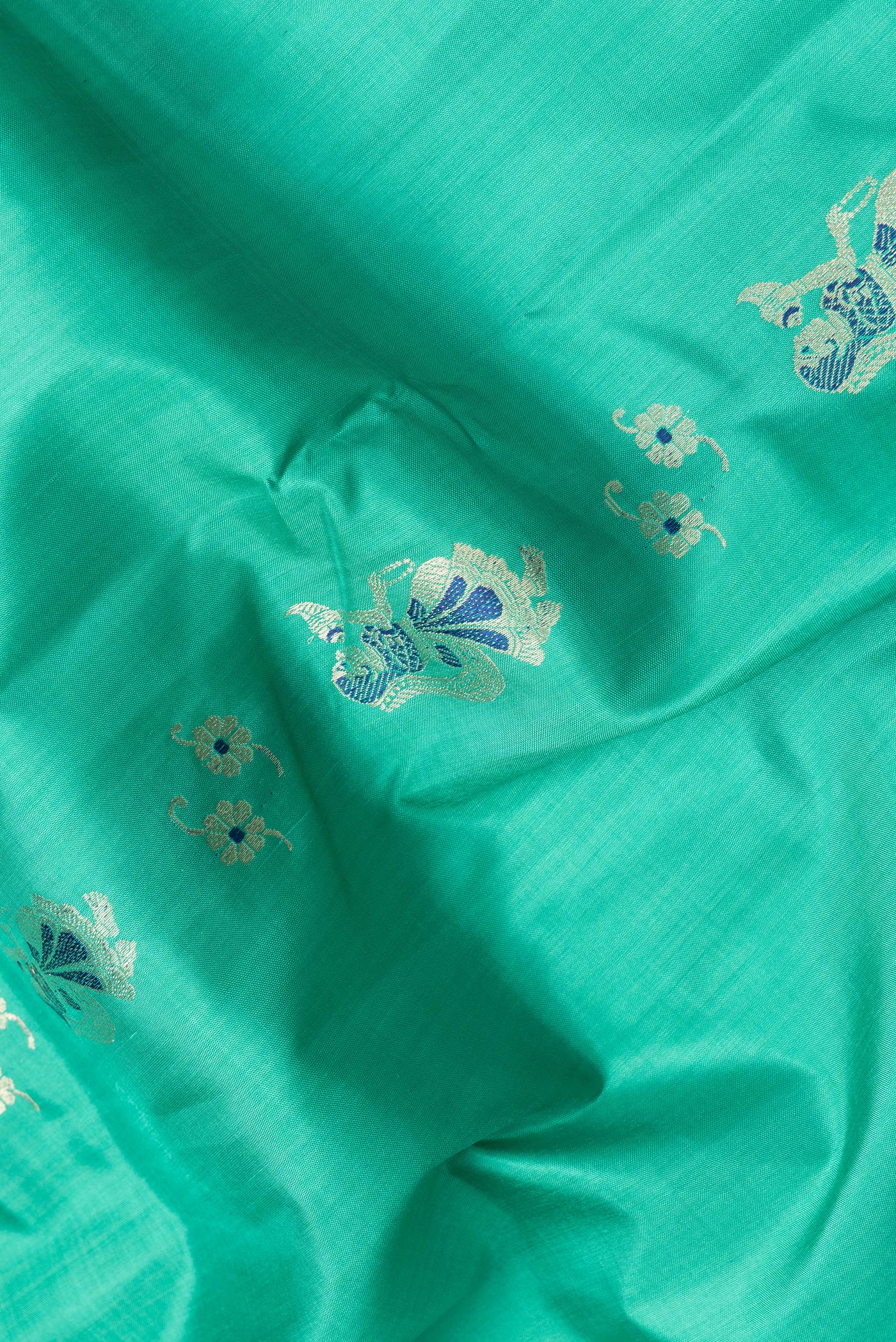 Close up of Sea Green Dual Tone Baluchari Silk Saree with Zari And Thread Butta on the body and Fancy Border.  displaying folds