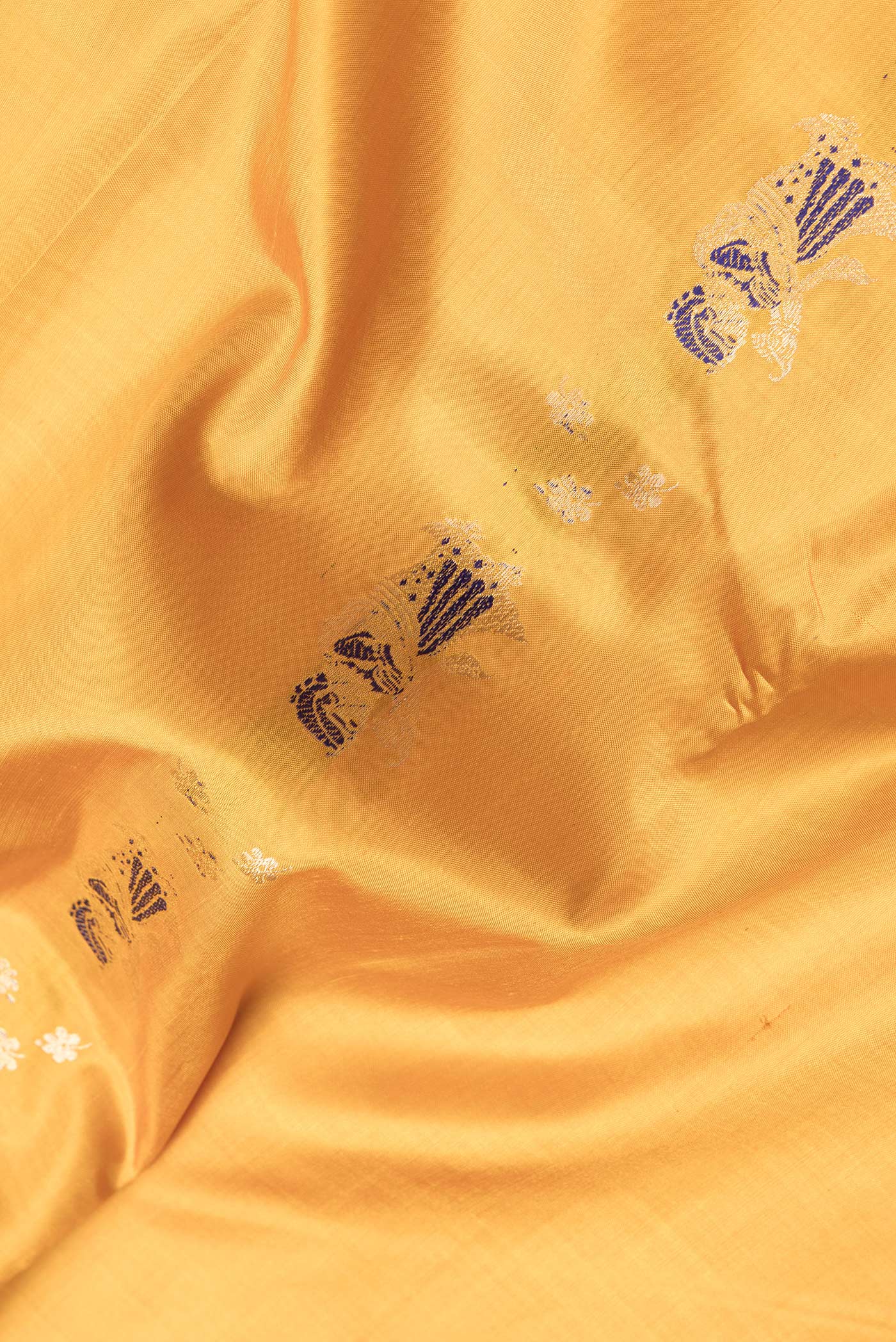 Close up of Mustard Dual Tone Baluchari Silk Saree with Zari And Thread Butta on the body and Fancy Border.  displaying folds