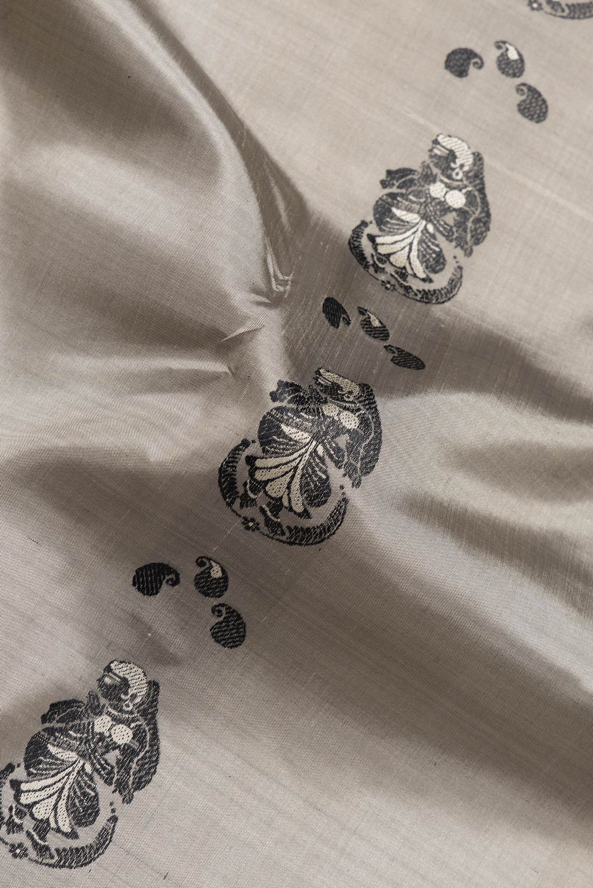 Close up of Grey Dual Tone Baluchari Silk Saree with Thread Butta on the body and Fancy Border.  displaying folds