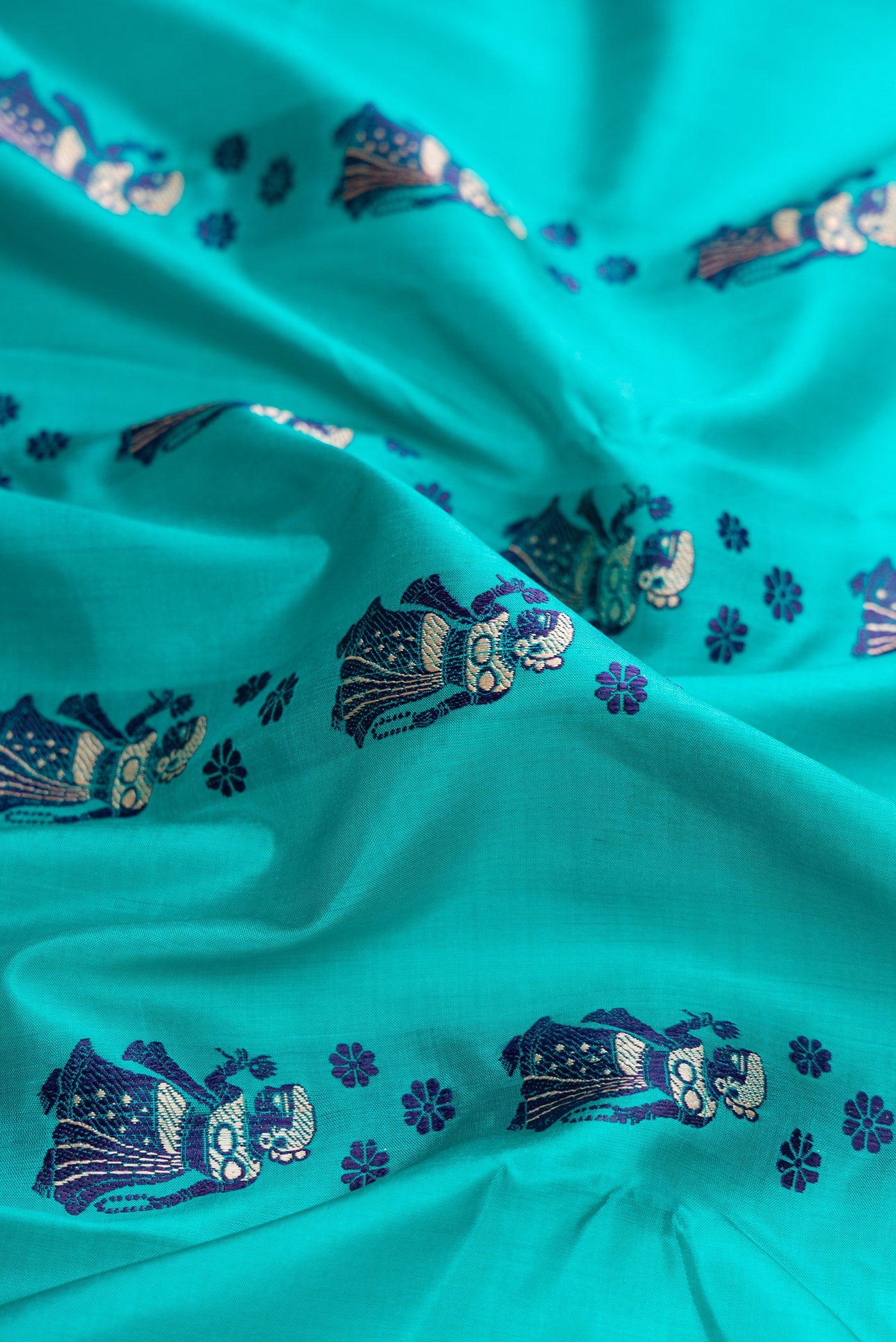 Close up of Sky Blue Dual Tone Baluchari Silk Saree with Thread Butta on the body and Thread Border.  displaying folds