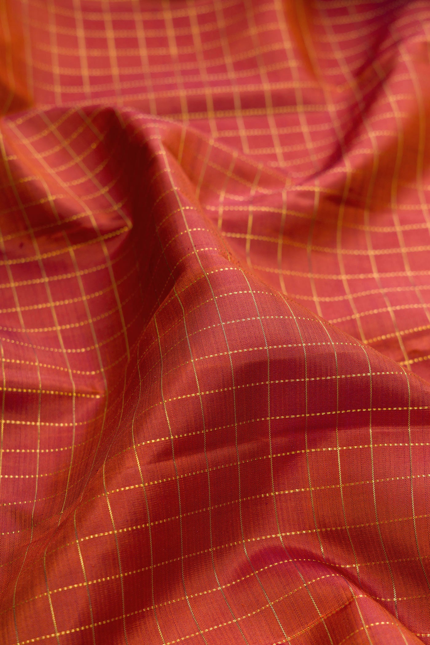 Close up of Brick Orange Dual Tone Kanjivaram Silk Saree with Checked design on the body and Zari Border.  displaying folds
