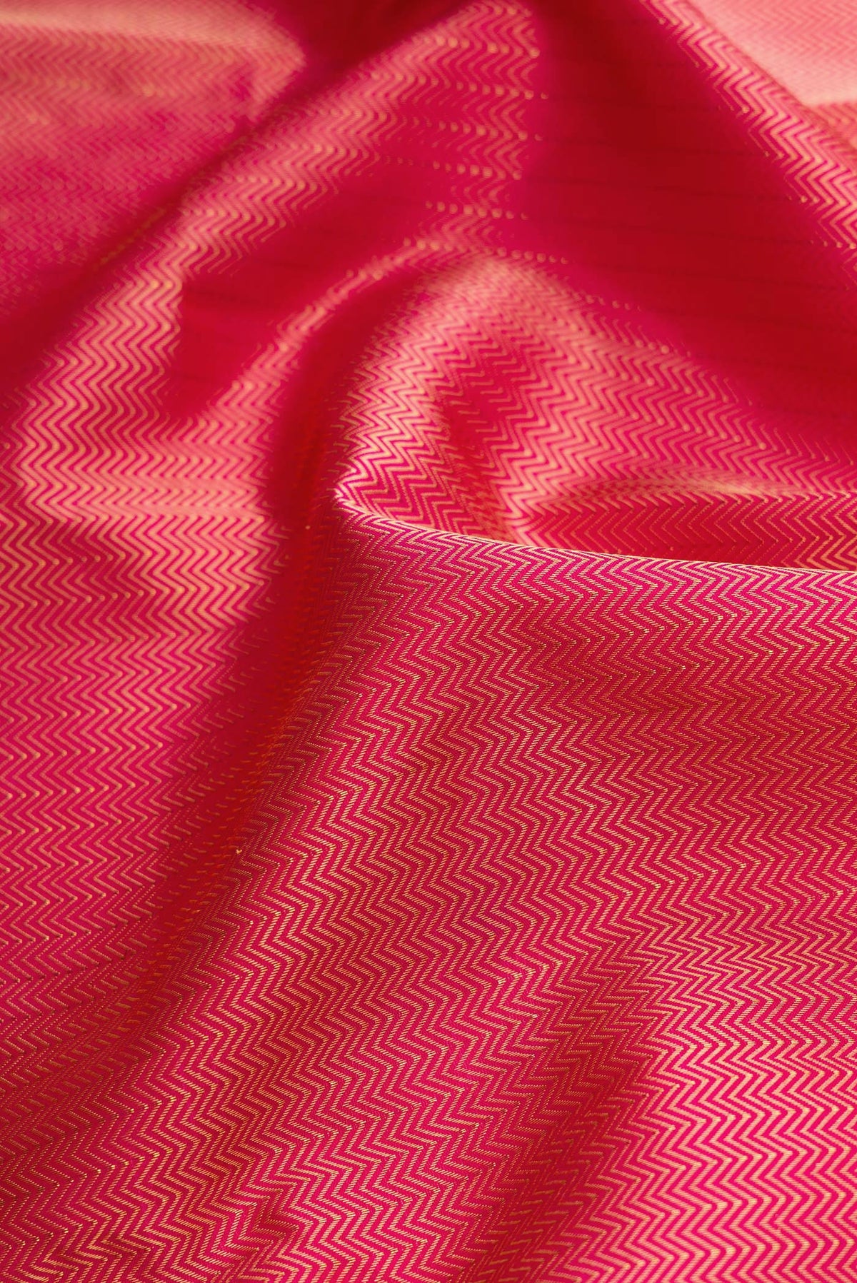 Close up of Dark Pink Dual Tone Kanchipuram Silk Saree with Jacquard design on the body and Zari Border.  displaying folds