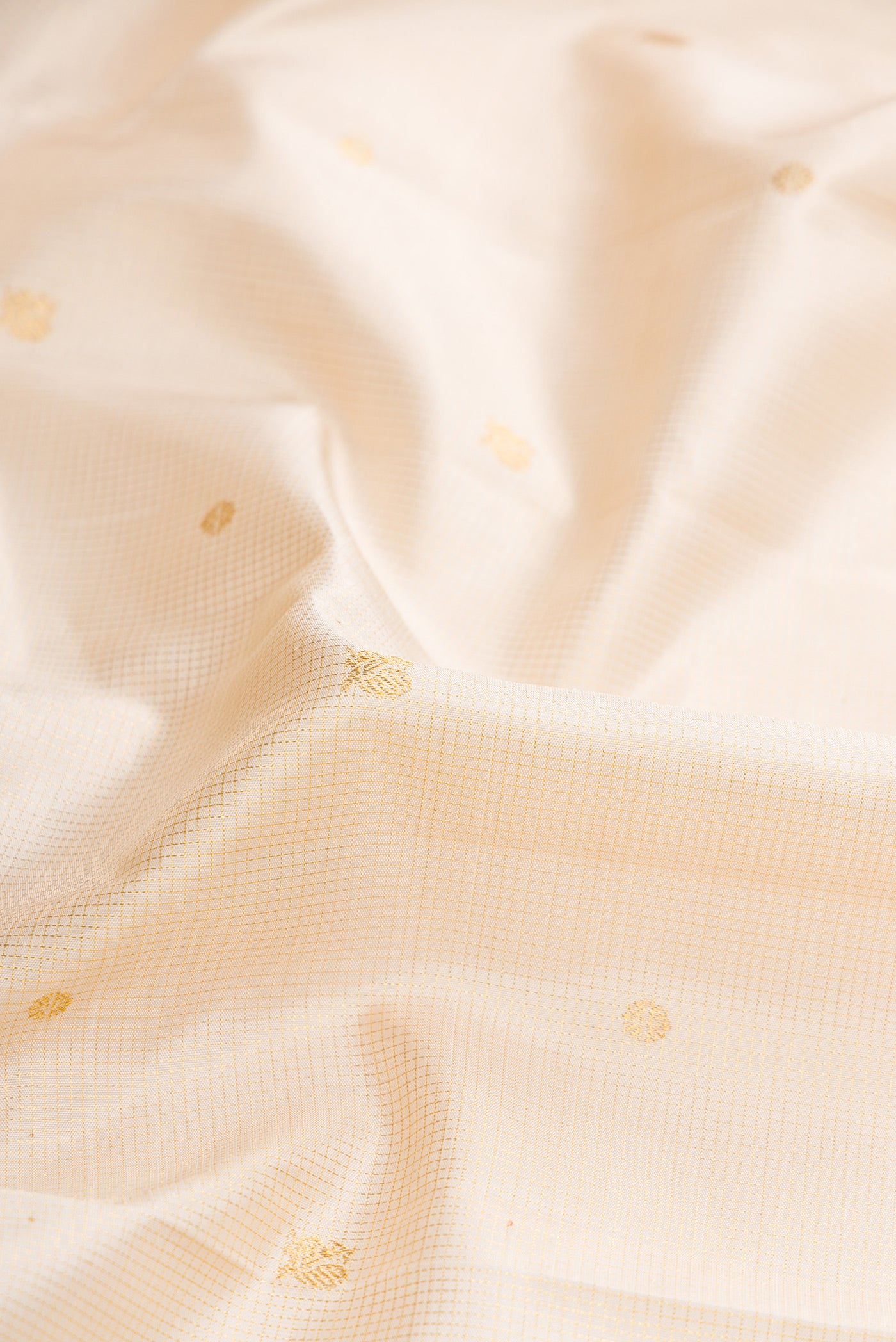 Close up of Beige Dual Tone Kanchipuram Silk Saree with Zari Butta on the body and Zari Border.  displaying folds