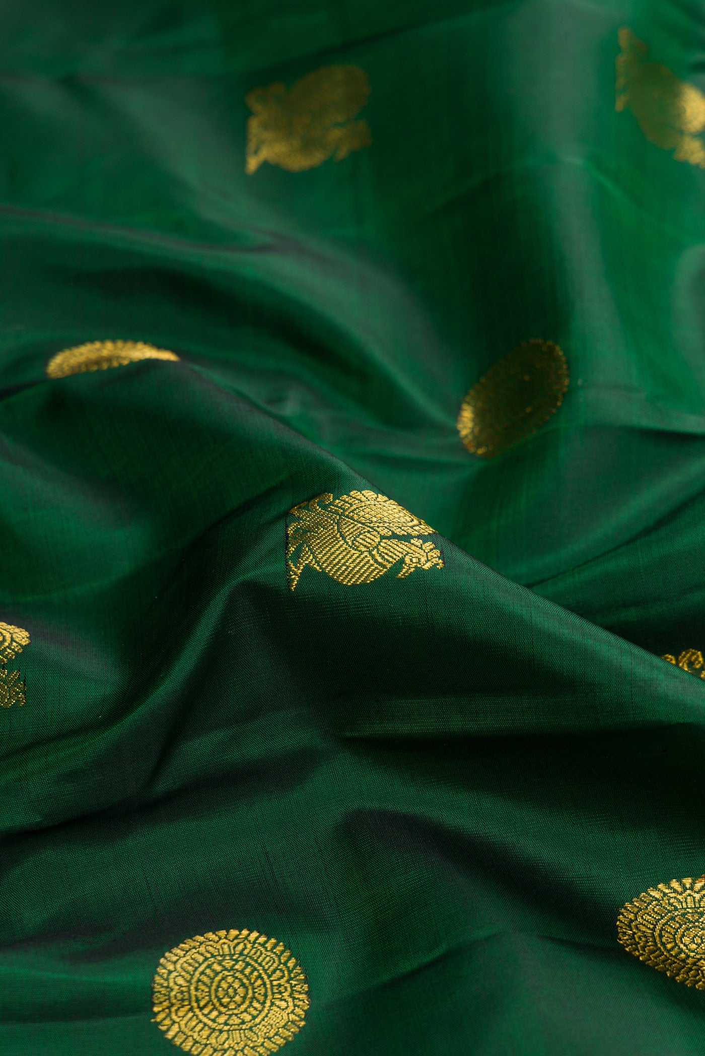Close up of Green Dual Tone Kanjivaram Silk Saree with Zari Butta on the body and Zari Border.  displaying folds