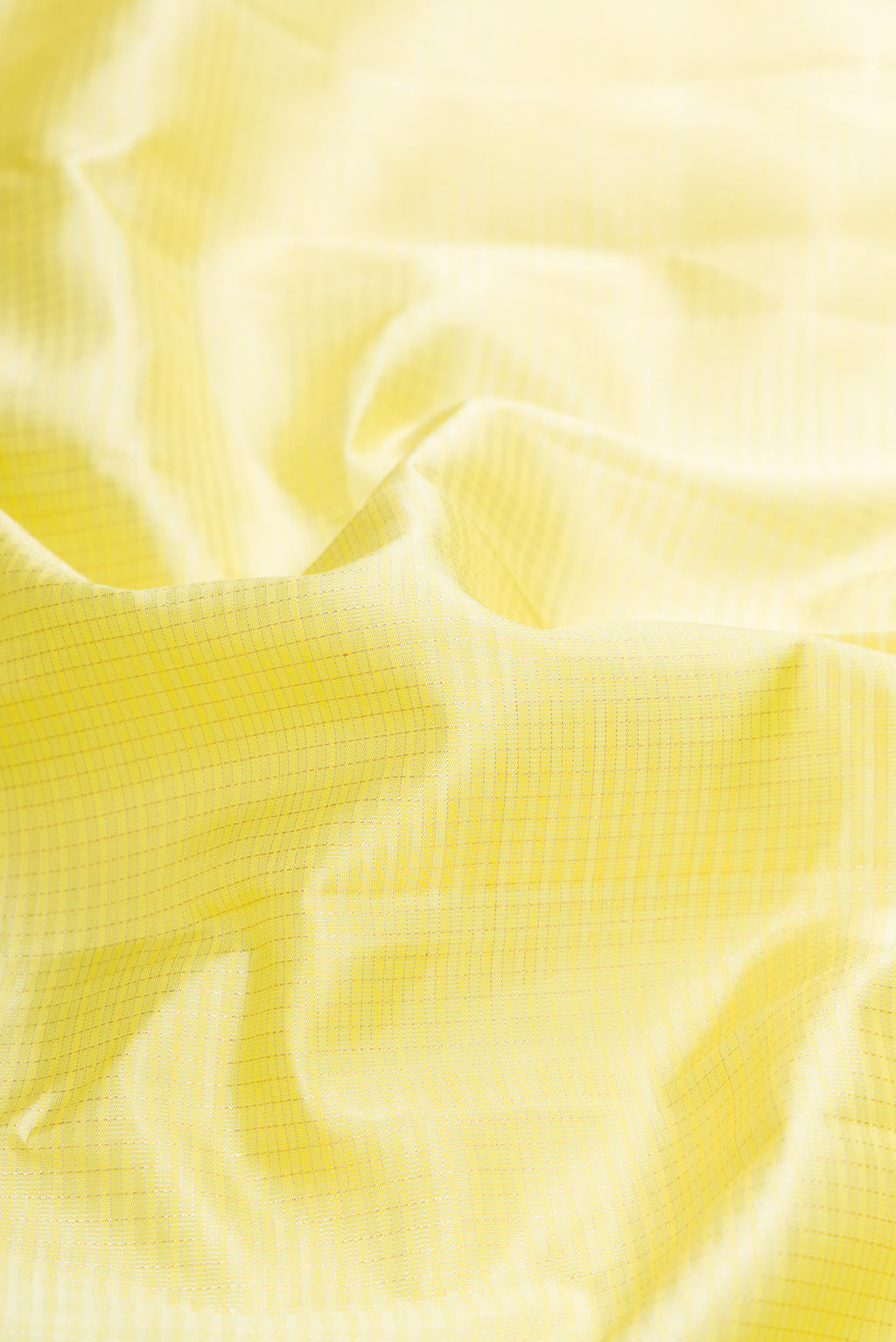 Close up of Lemon Yellow Dual Tone Kanchipuram Silk Saree with Checked design on the body and Zari Border.  displaying folds