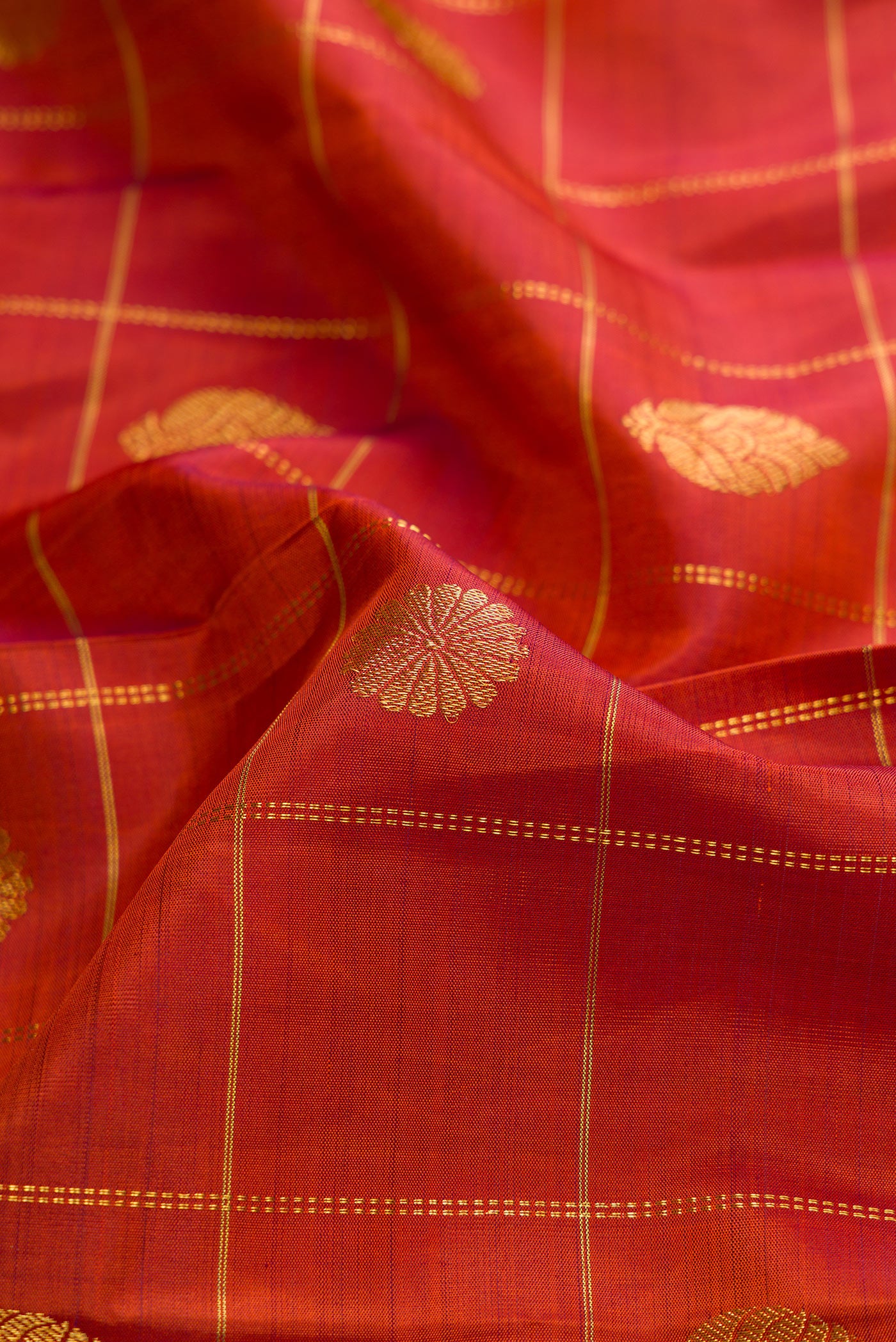 Close up of Brick Orange Dual Tone Kanjivaram Silk Saree with Checked design on the body and Zari Border.  displaying folds