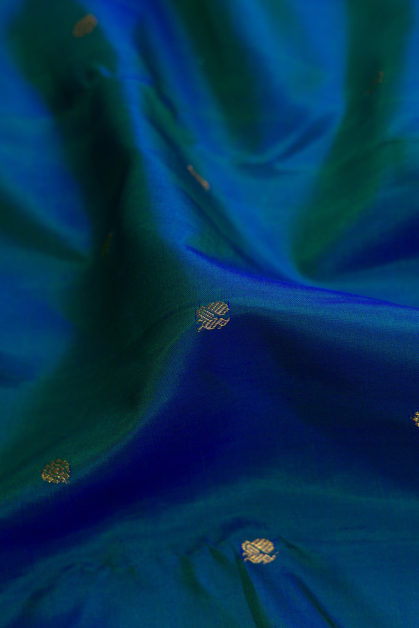 Close up of Peacock Blue Dual Tone Kanjivaram Silk Saree with Zari Butta on the body and Without Border.  displaying folds