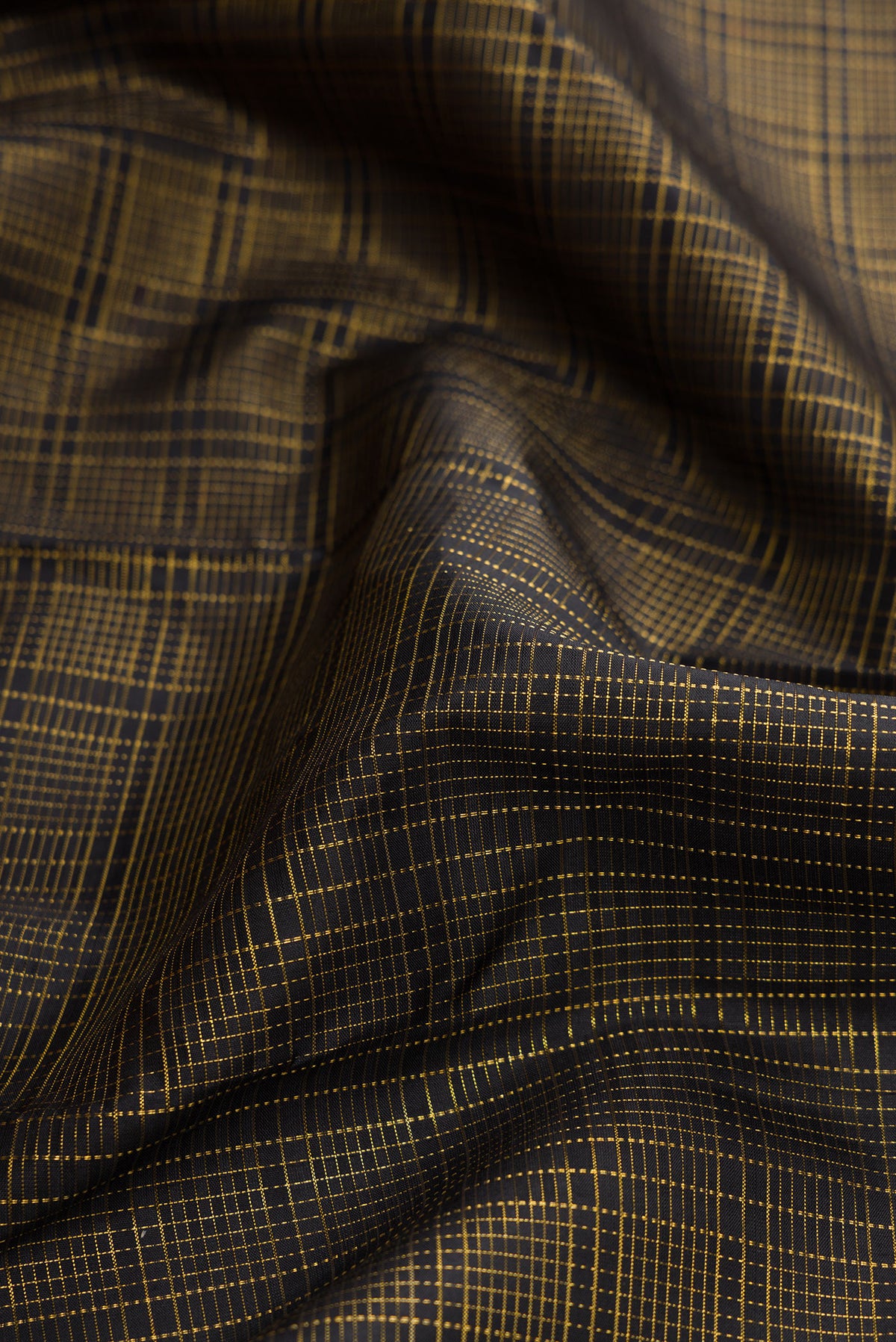 Close up of Black Dual Tone Kanjivaram Silk Saree with Checked design on the body and Zari Border.  displaying folds