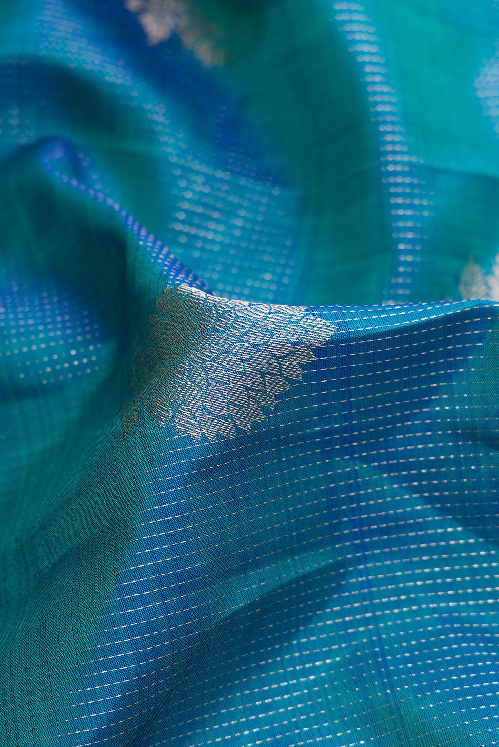 Close up of Peacock Blue Dual Tone Kanjivaram Silk Saree with Zari Butta on the body and Zari Border.  displaying folds