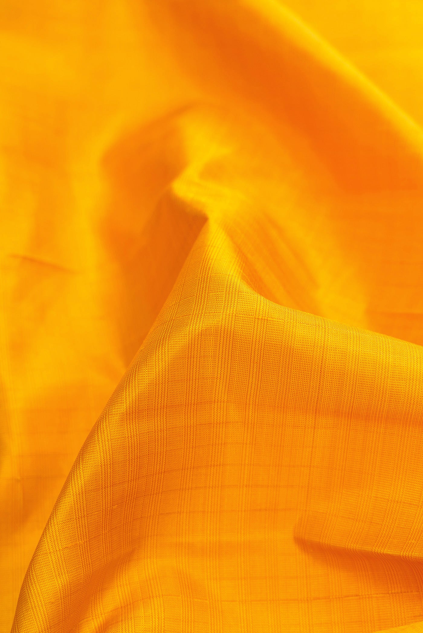 Close up of Yellow Dual Tone Kanjivaram Silk Saree with Checked design on the body and Zari Border.  displaying folds