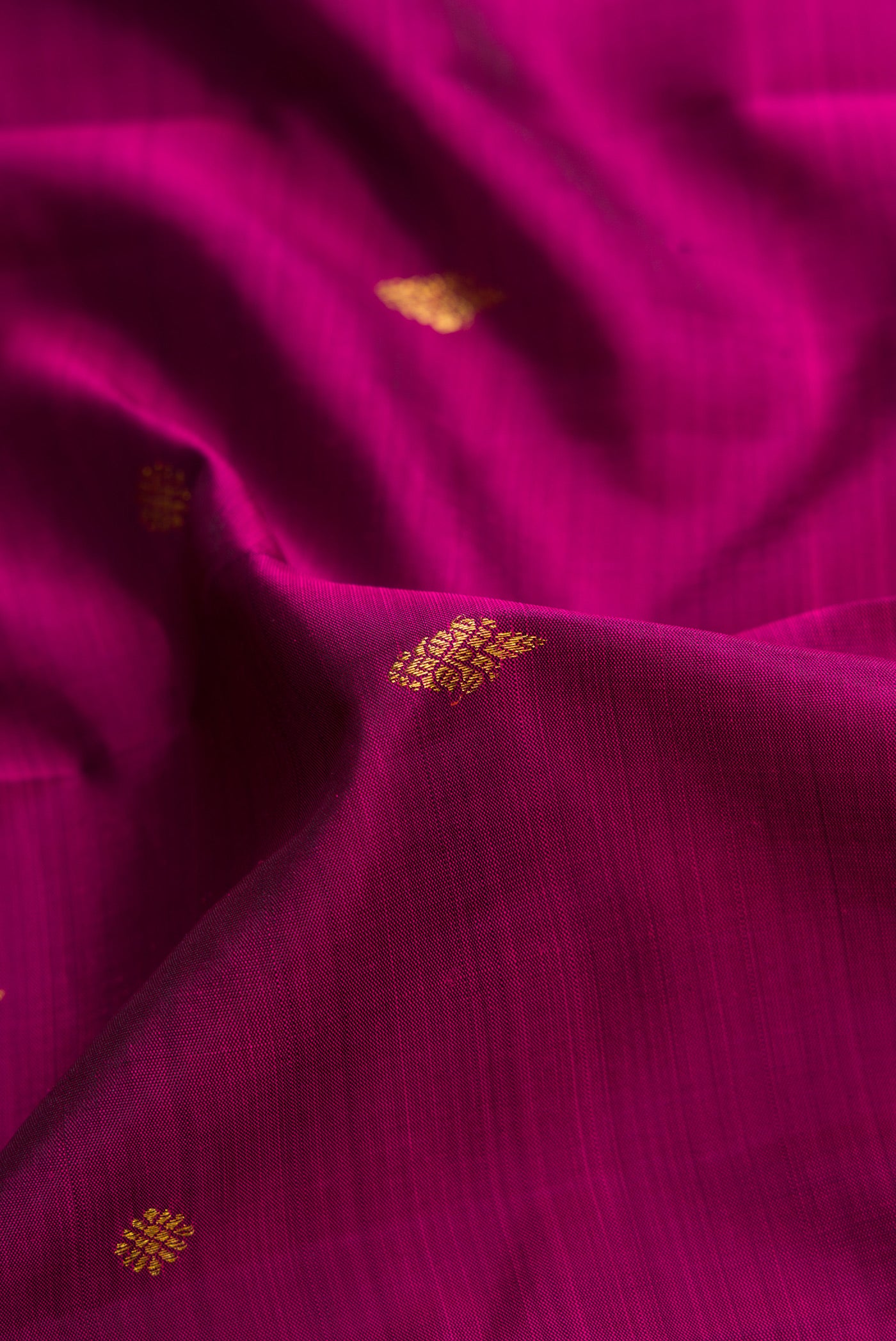 Close up of Magenta Dual Tone Kanjivaram Silk Saree with Zari Butta on the body and Fancy Border.  displaying folds