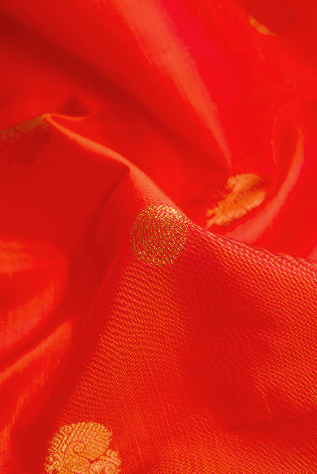 Close up of Orange Dual Tone Kanjivaram Silk Saree with Zari Butta on the body and Zari Border.  displaying folds