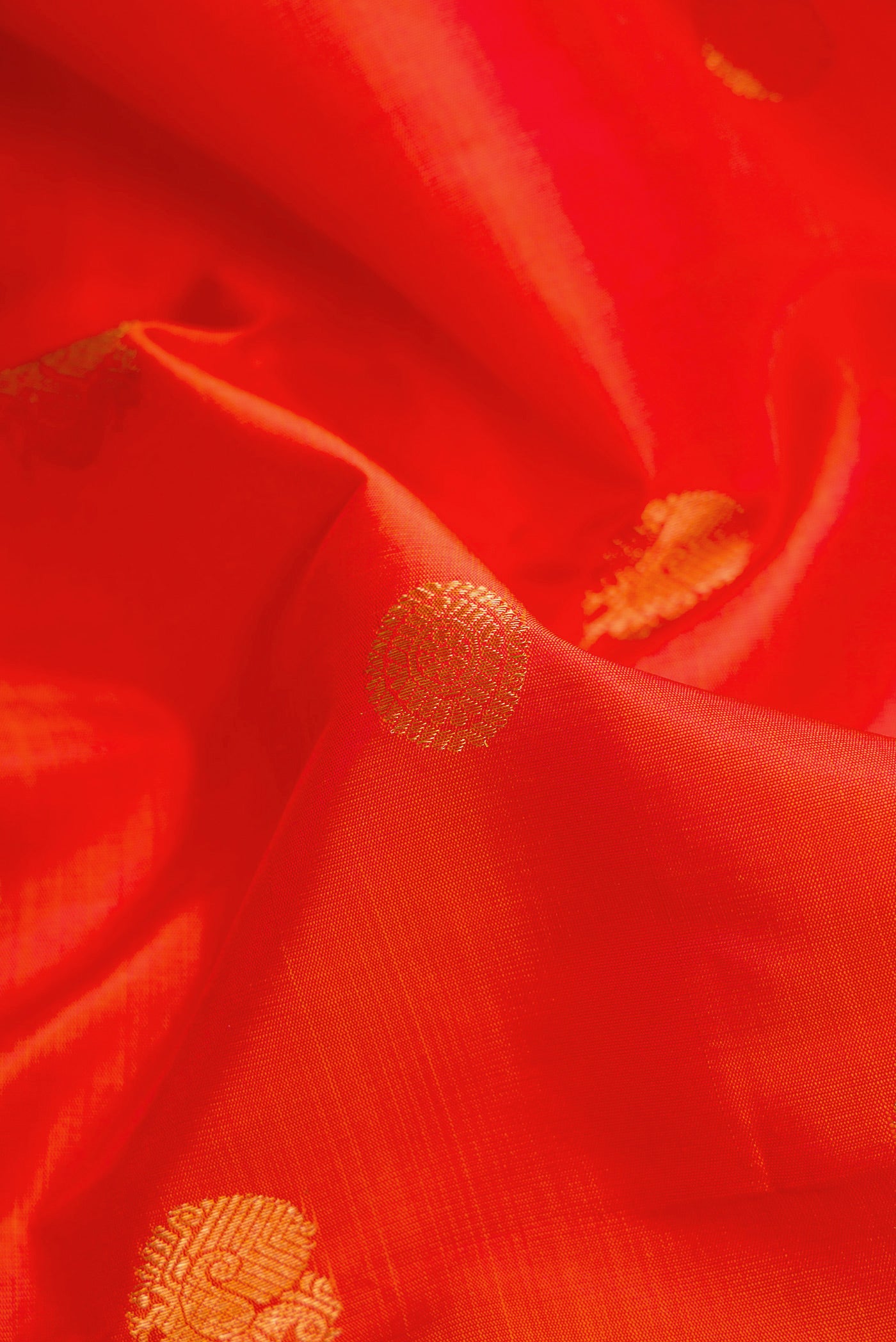 Close up of Orange Dual Tone Kanjivaram Silk Saree with Zari Butta on the body and Zari Border.  displaying folds