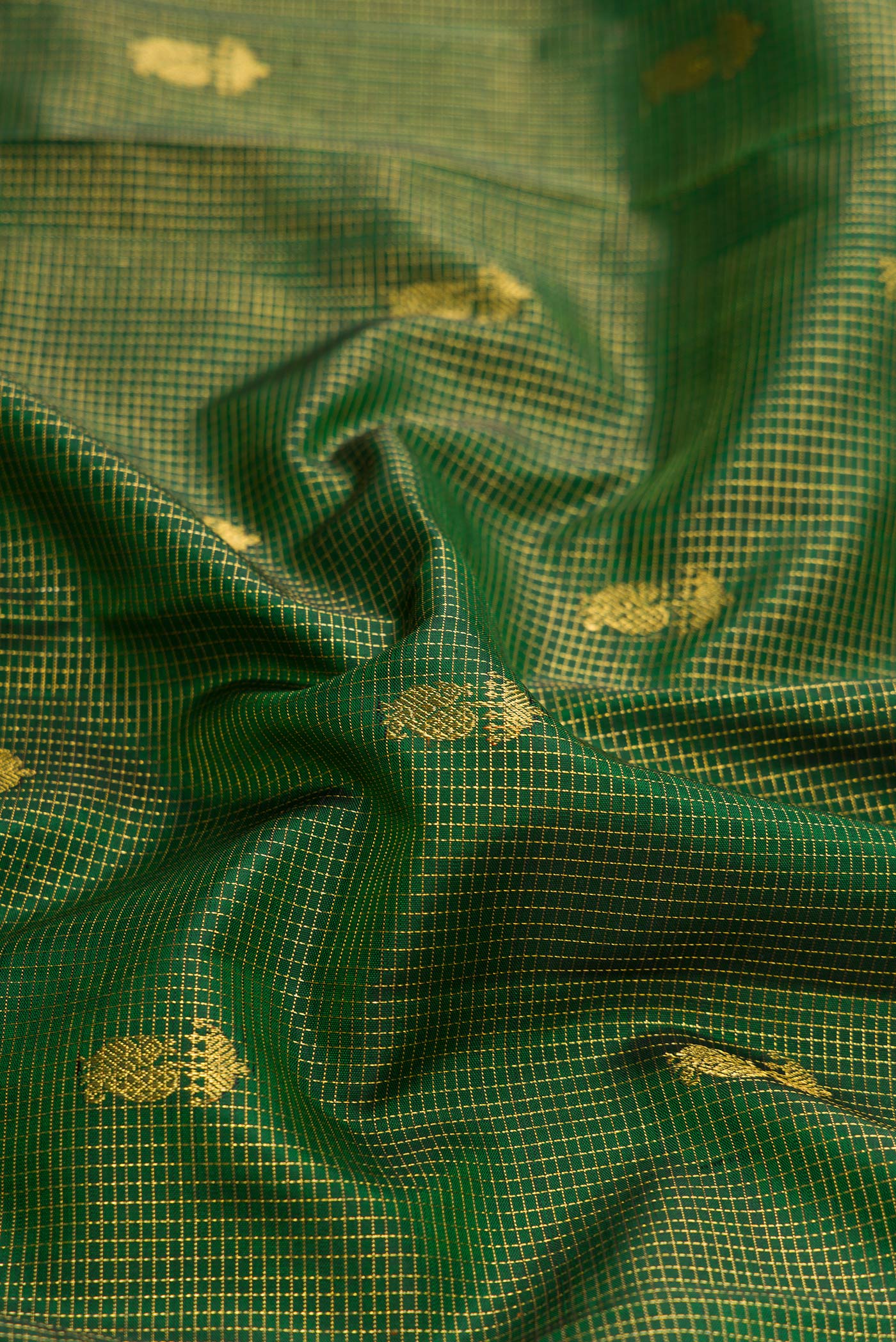 Close up of Bottle Green Dual Tone Kanchipuram Silk Saree with Checked design on the body and Zari Border.  displaying folds