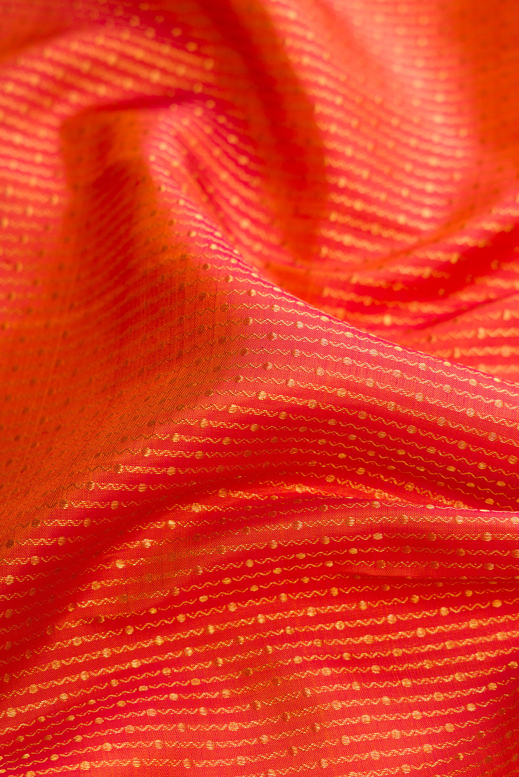 Close up of Brick Orange Dual Tone Kanchipuram Silk Saree with Zari Brocade on the body and Zari Border.  displaying folds