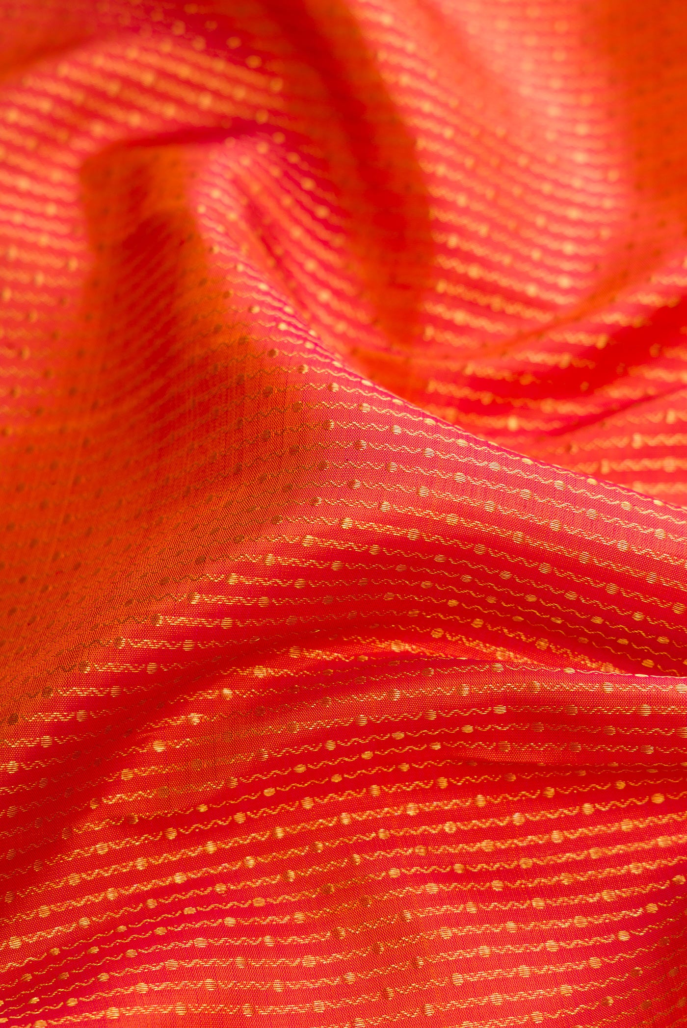 Close up of Brick Orange Dual Tone Kanchipuram Silk Saree with Zari Brocade on the body and Zari Border.  displaying folds