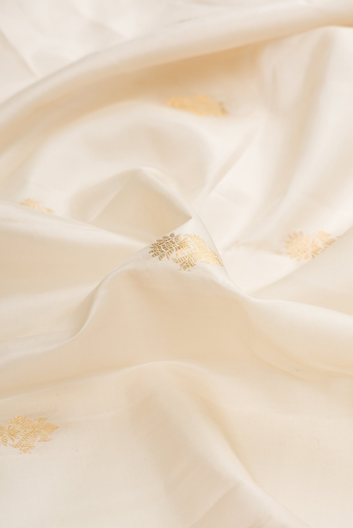 Close up of Off White Dual Tone Kanchipuram Silk Saree with Zari Butta on the body and Zari Border.  displaying folds