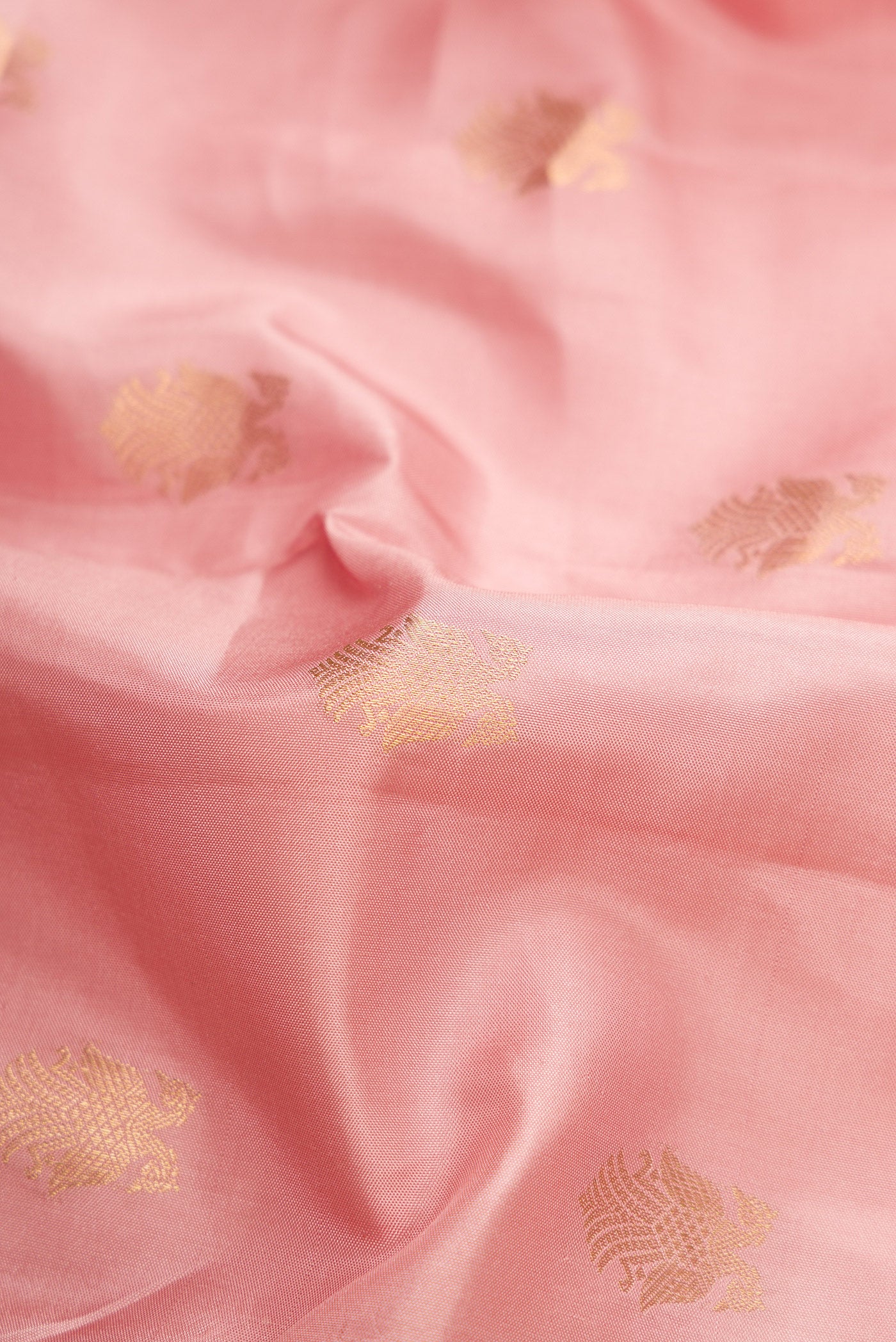 Close up of Rose Gold Dual Tone Kanchipuram Silk Saree with Zari Butta on the body and Zari Border.  displaying folds