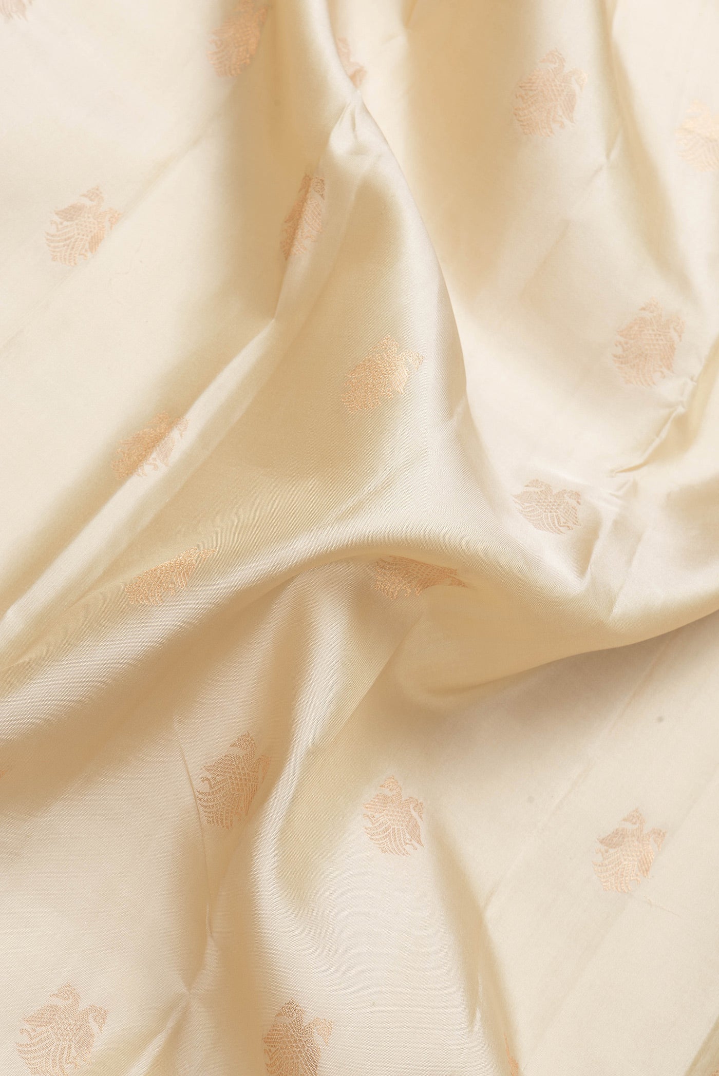Close up of Beige Dual Tone Kanchipuram Silk Saree with Zari Butta on the body and Zari Border.  displaying folds