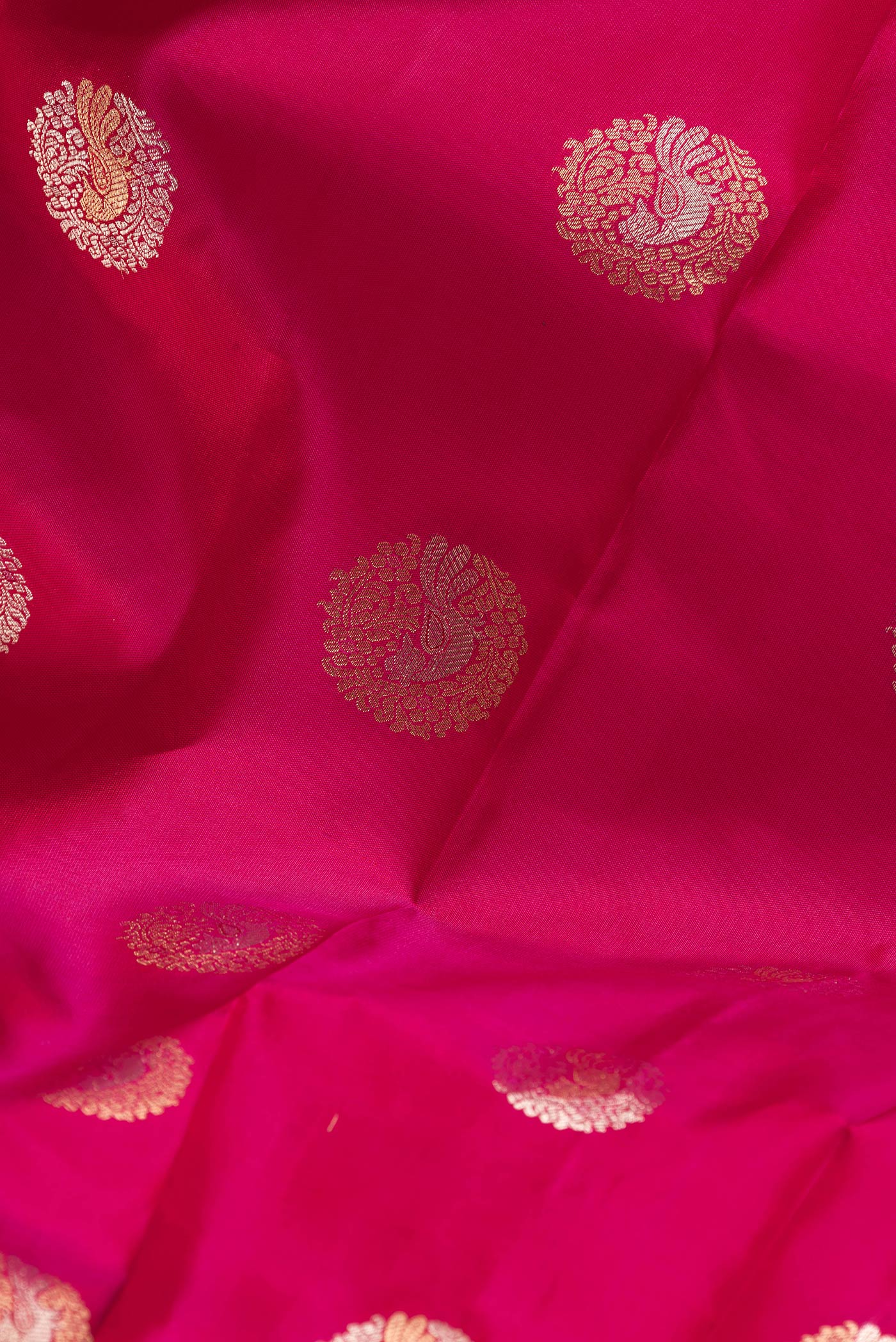 Close up of Dark Pink Dual Tone Kanjivaram Silk Saree with Zari Butta on the body and Fancy Border.  displaying folds