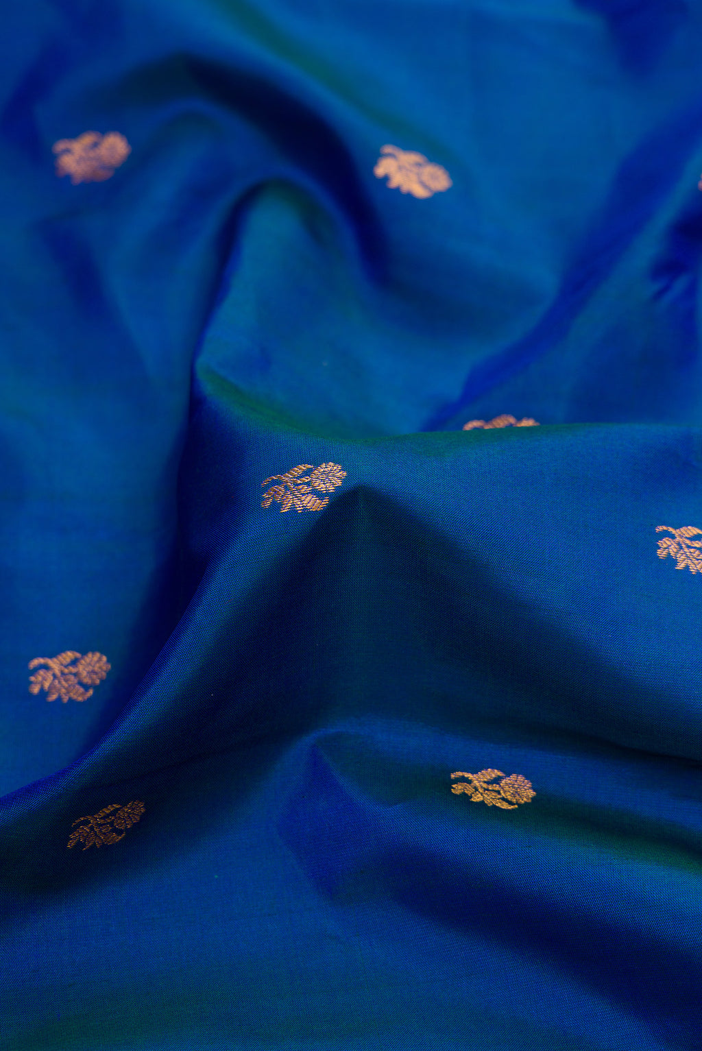 Close up of Peacock Blue Dual Tone Gadwal Silk Saree with Zari Butta on the body and Temple Border.  displaying folds