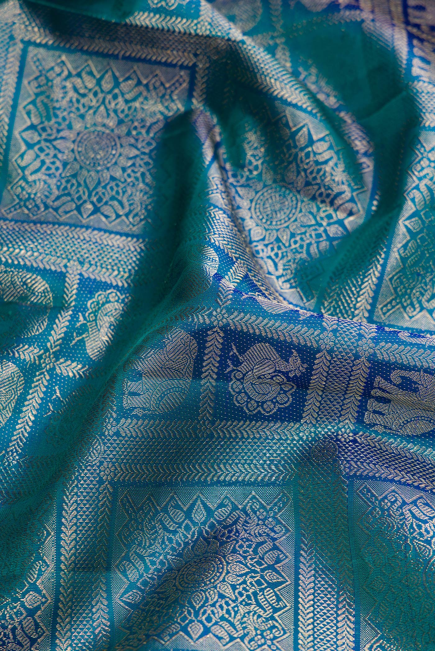 Close up of Peacock Blue Dual Tone Kanchipuram Silk Saree with Zari Brocade on the body and Zari Border.  displaying folds