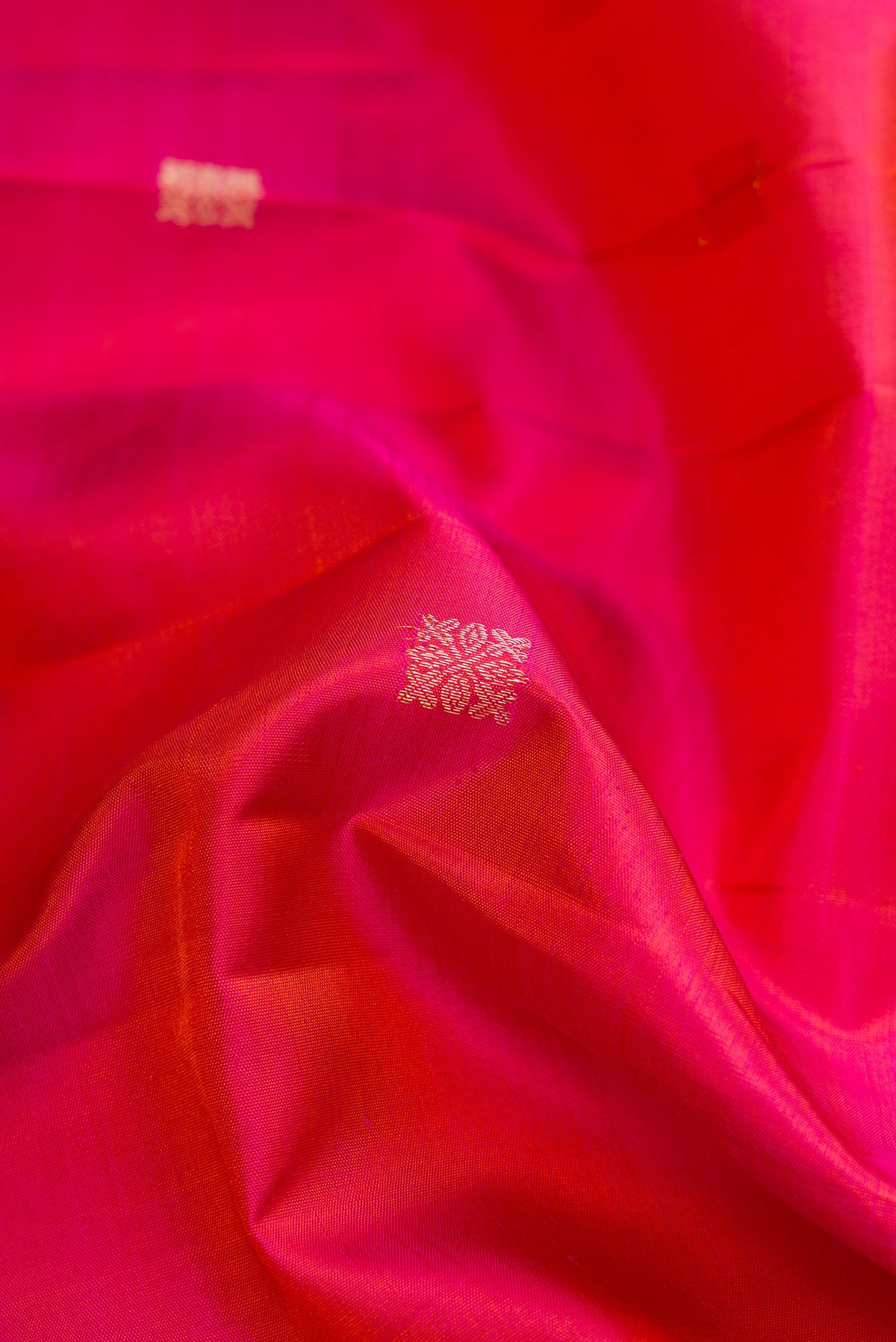 Close up of Coral Dual Tone Kanjivaram Silk Saree with Zari Butta on the body and Fancy Border.  displaying folds