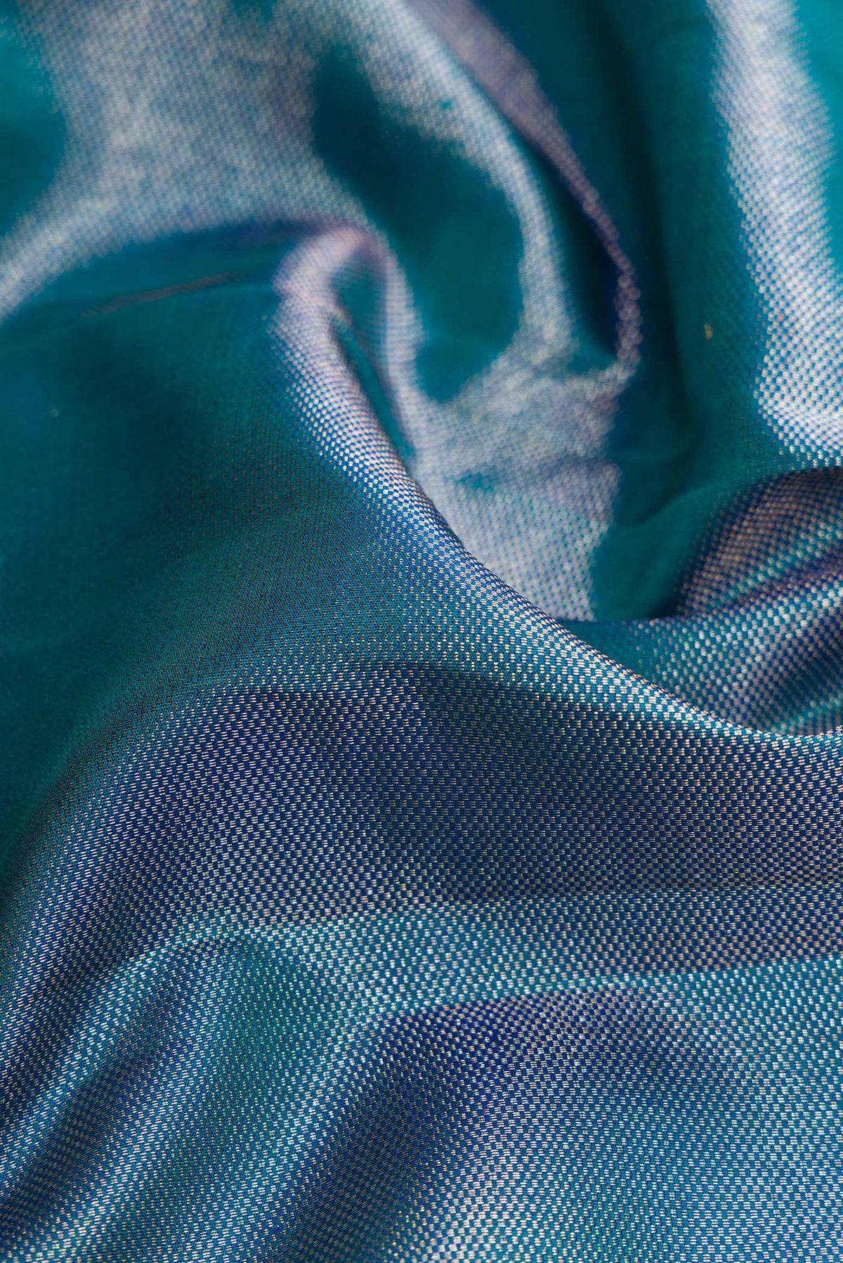 Close up of Peacock Blue Dual Tone Kanchipuram Silk Saree with Zari Brocade on the body and Fancy Border.  displaying folds