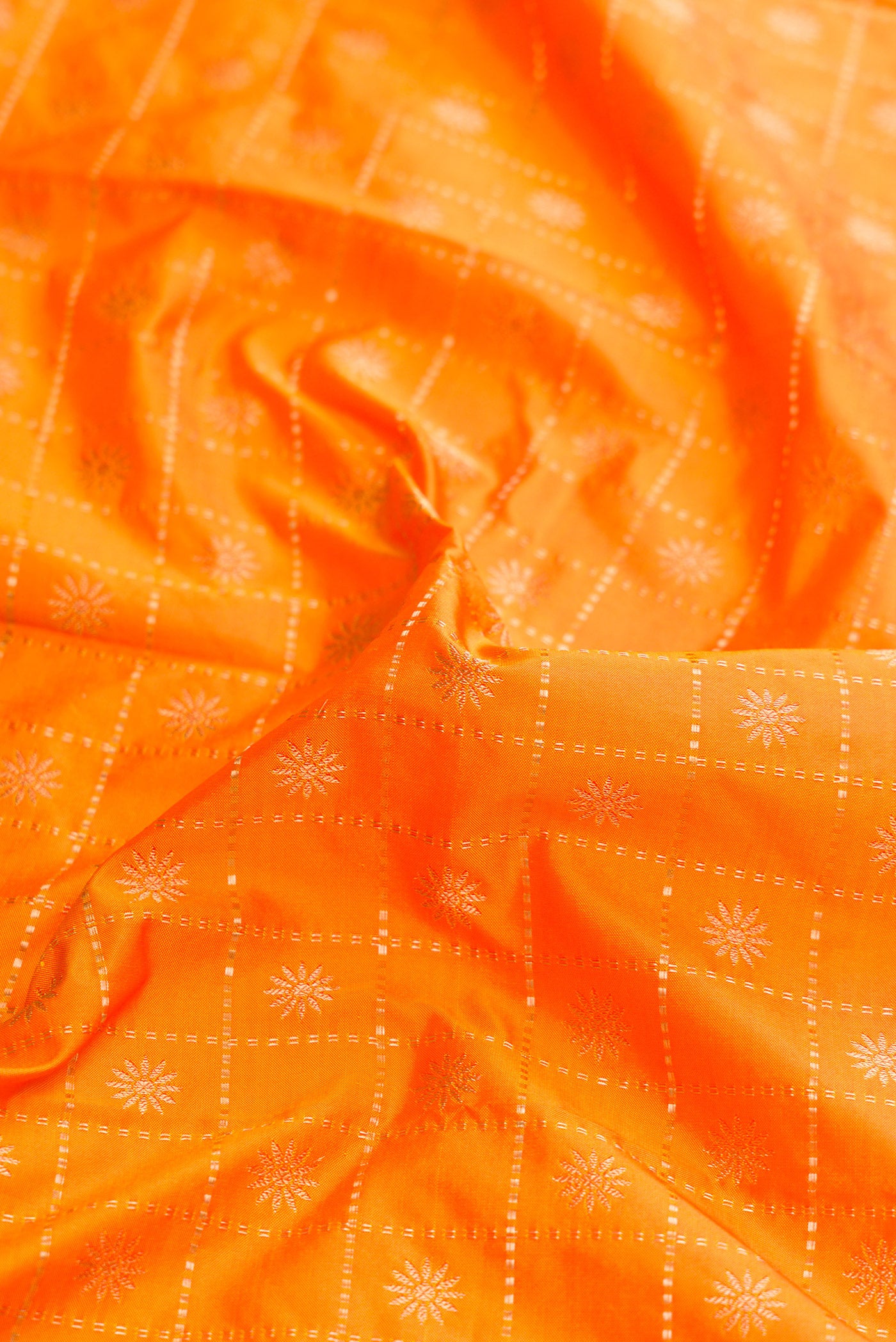 Close up of Orange Dual Tone Paithani Silk Saree with Zari Butta on the body and Paithani Border.  displaying folds